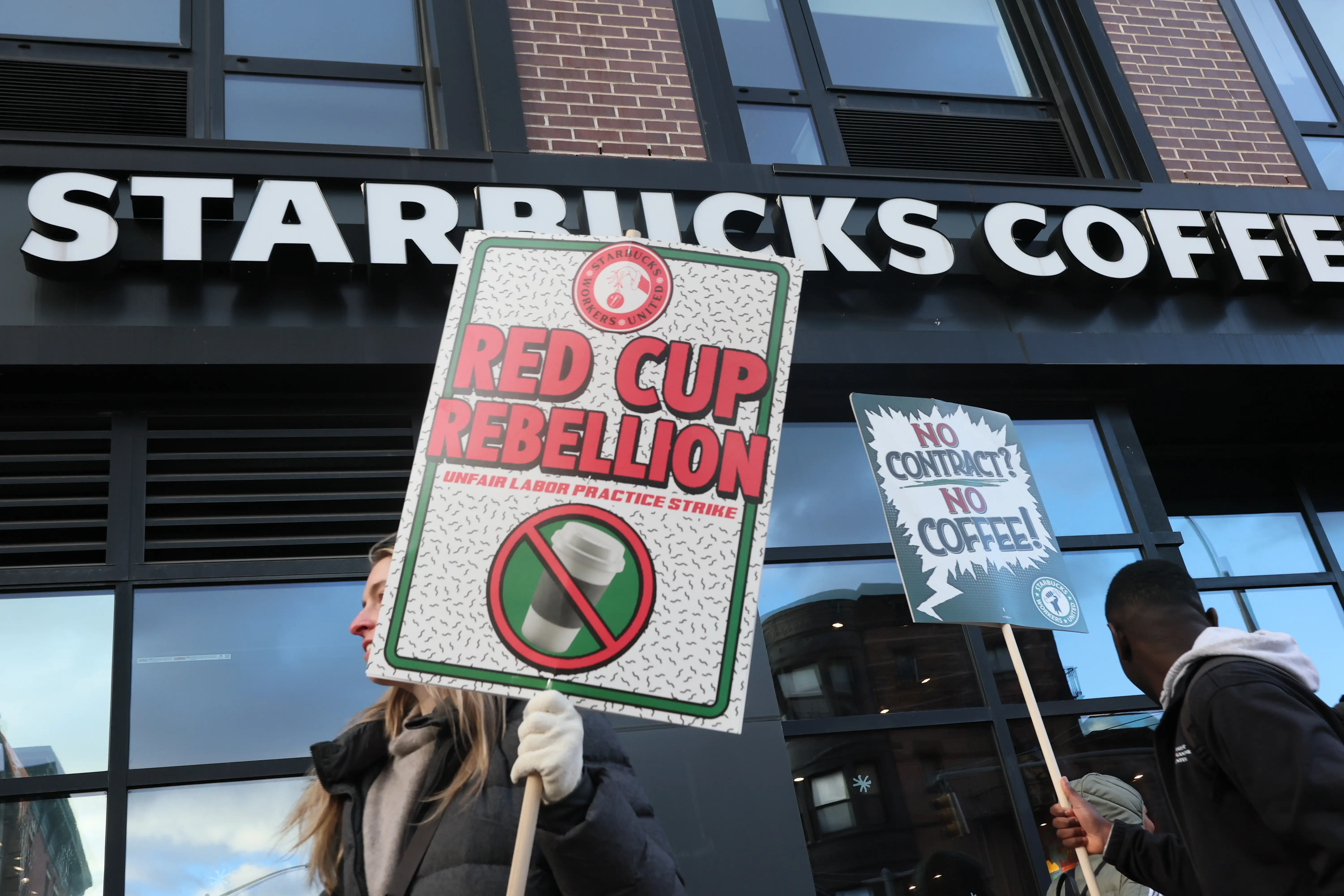 Protesters hold picket signs outside a Starbucks store.