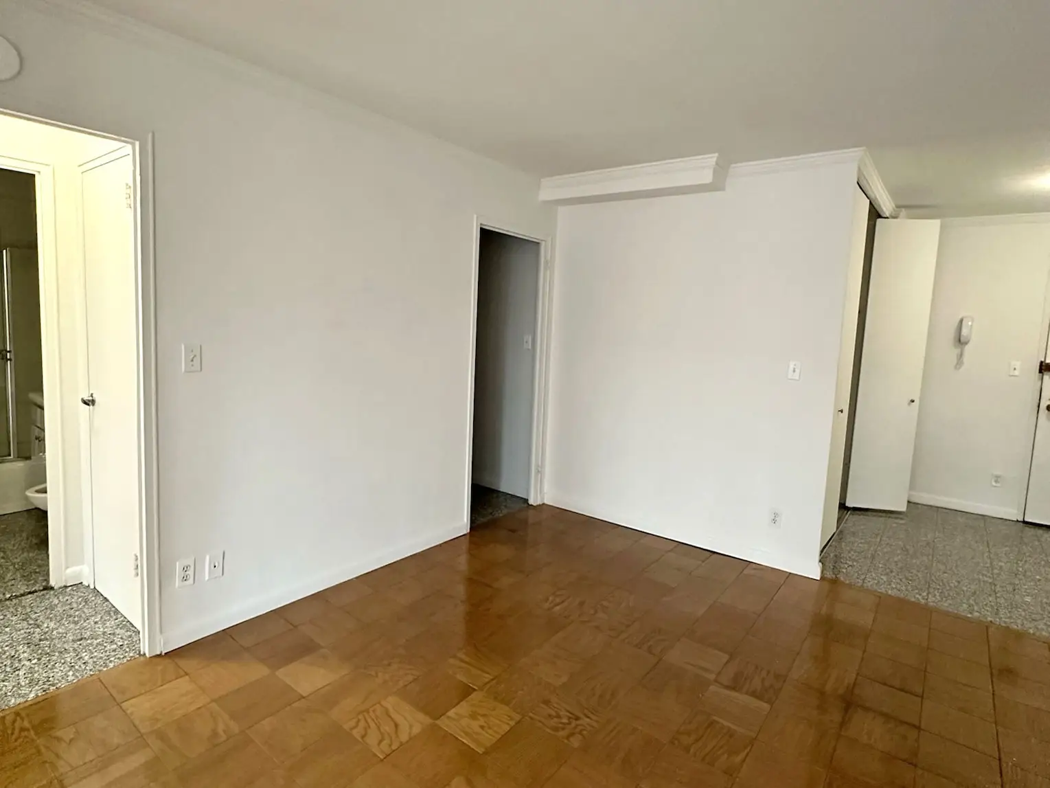 An empty apartment with white walls and wooden floors.