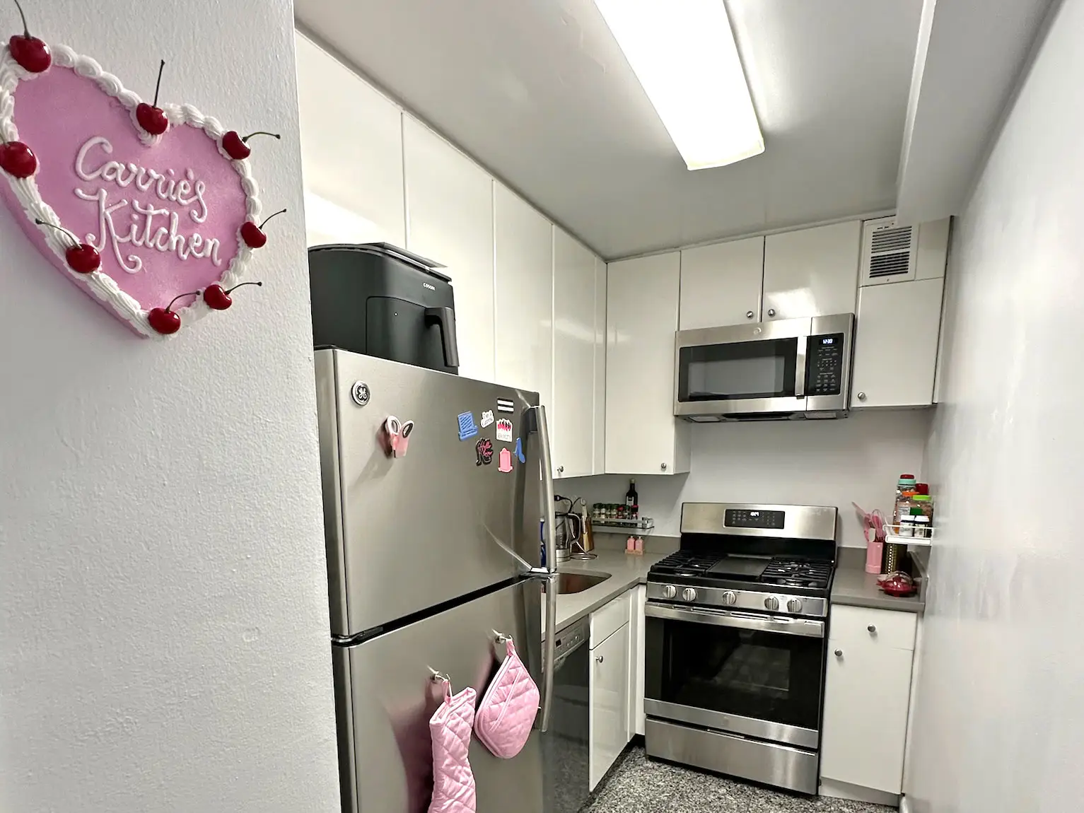 A small kitchen with a heart-shaped sign on the wall that reads 