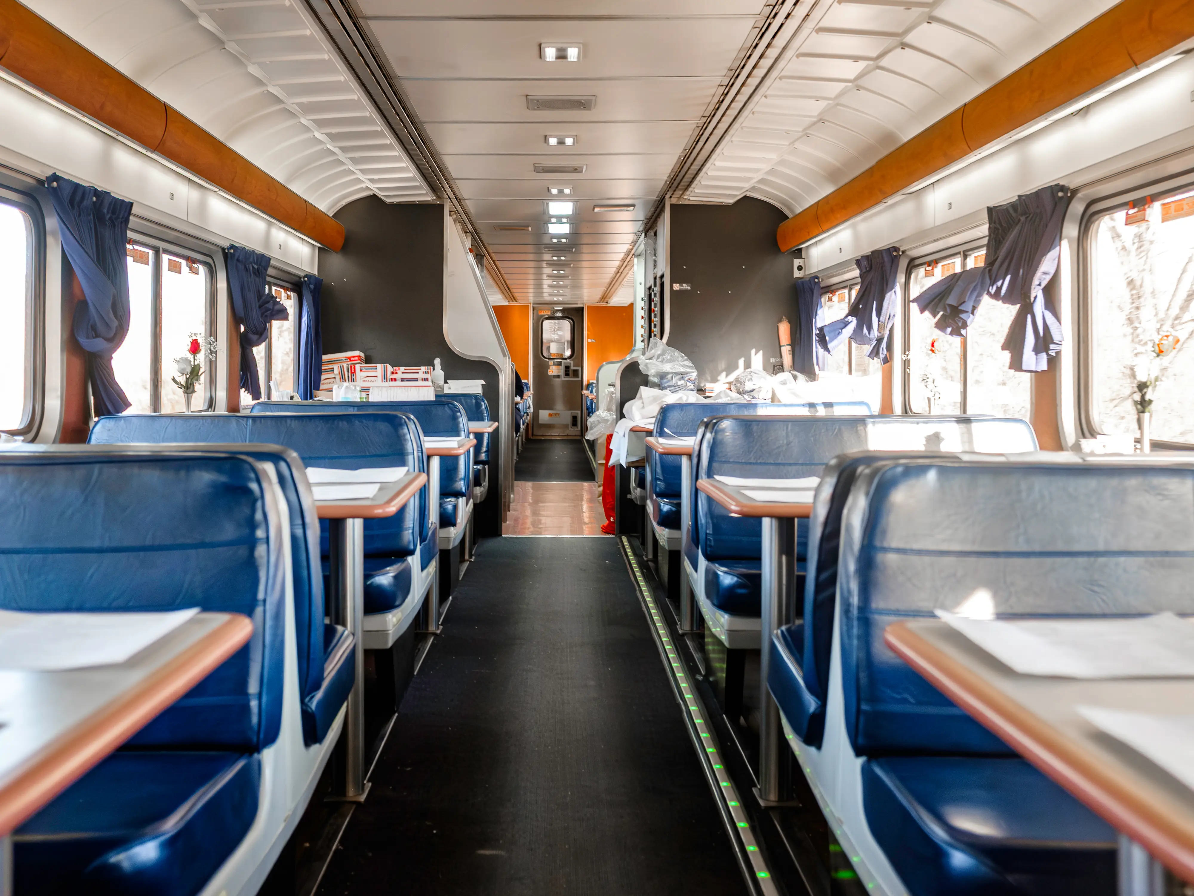 Inside an empty train dining car with blue booths
