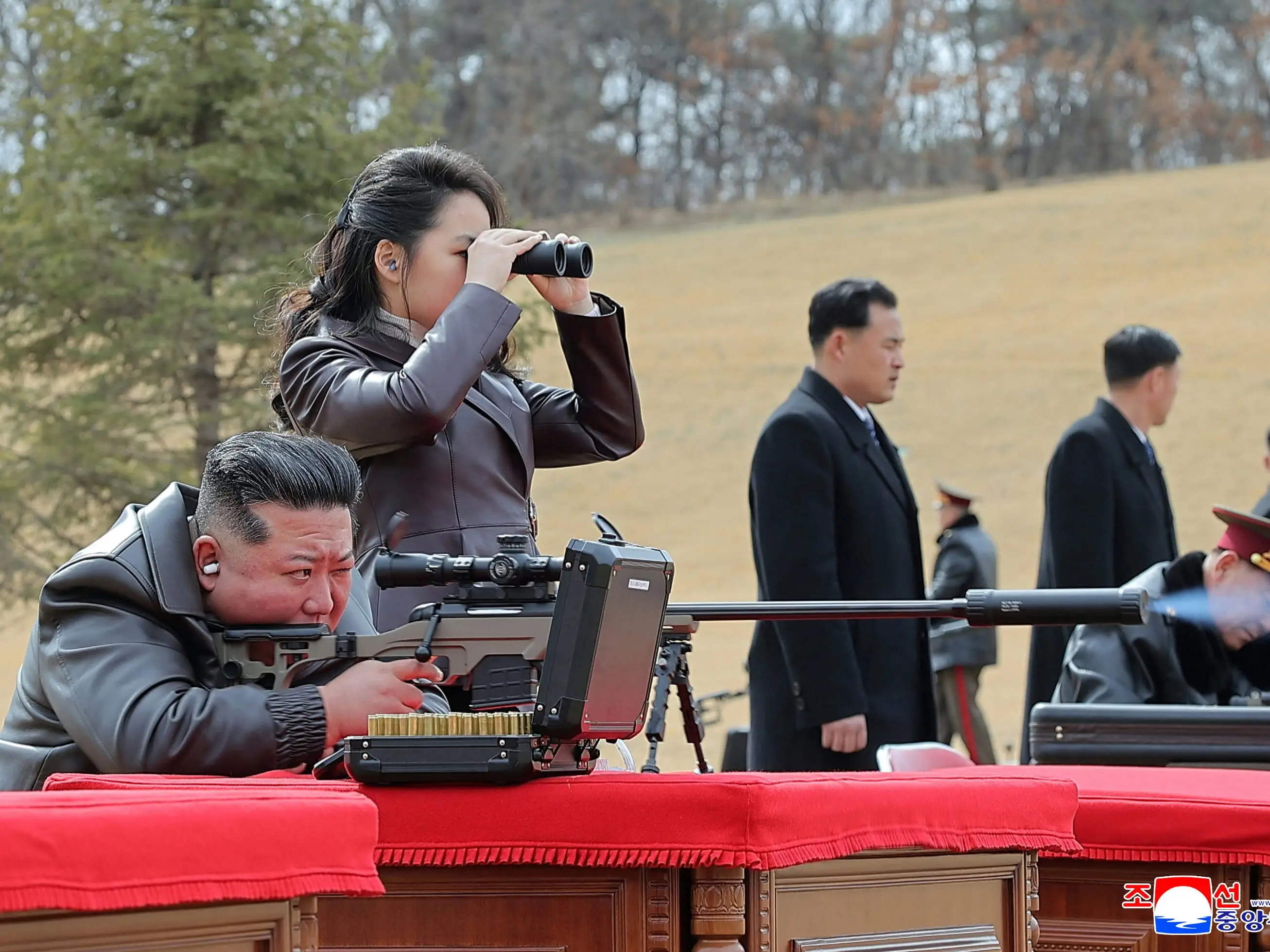 Kim Jong Un fires a rifle as his daughter, Kim Ju Ae, watches with binoculars.