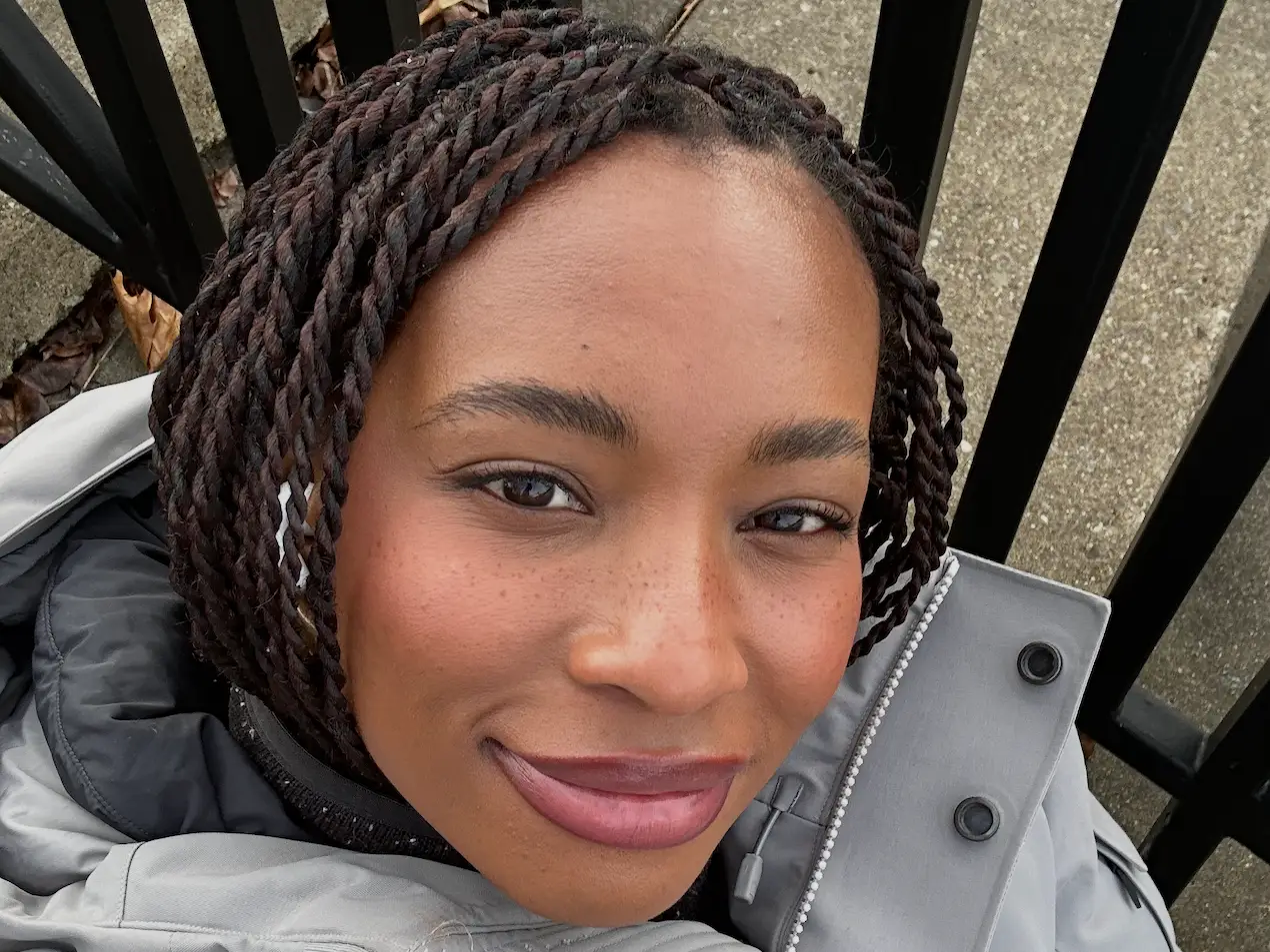 Camillia Nwokedi smiling, wearing a gray coat outside.