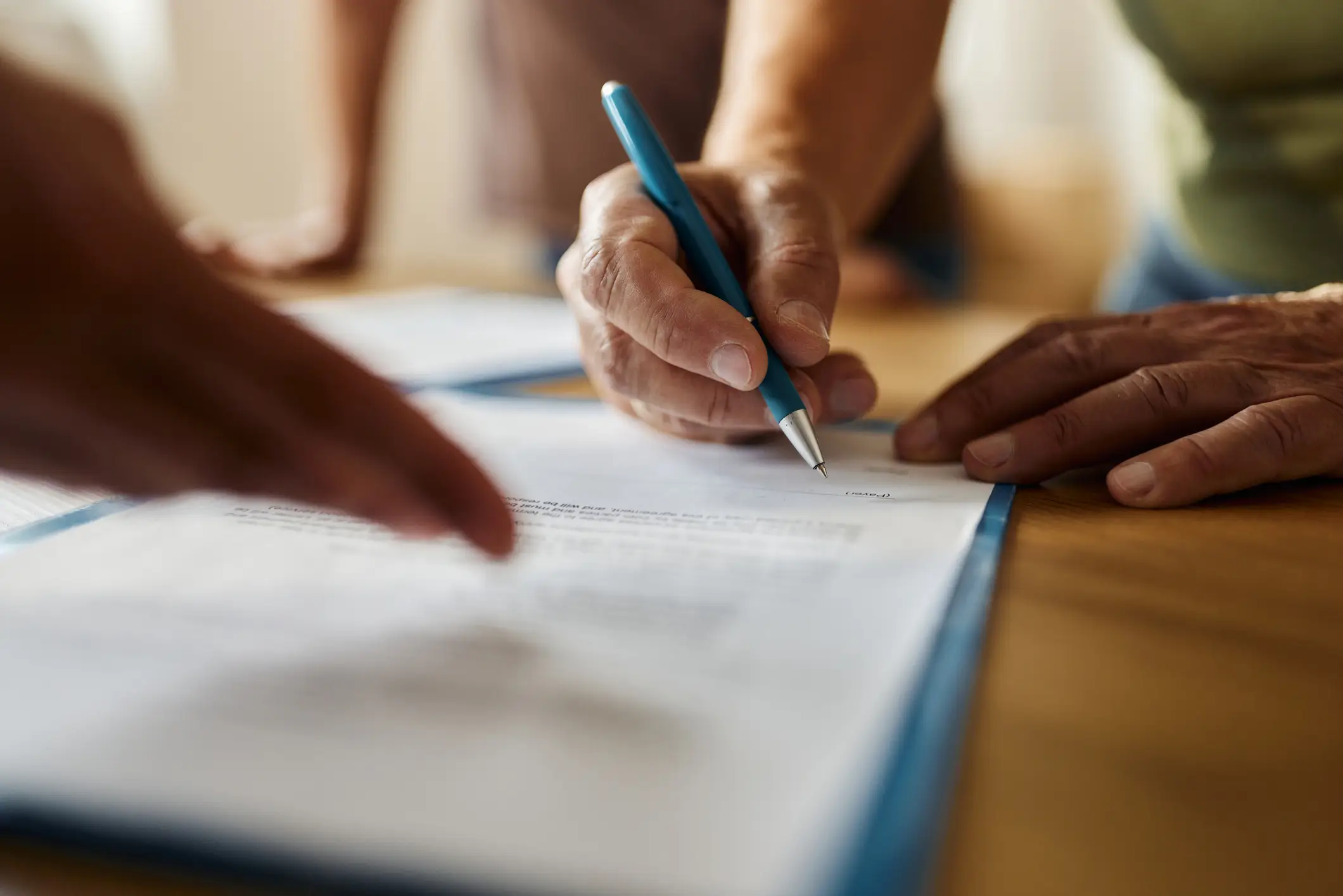 hands signing a piece of paper