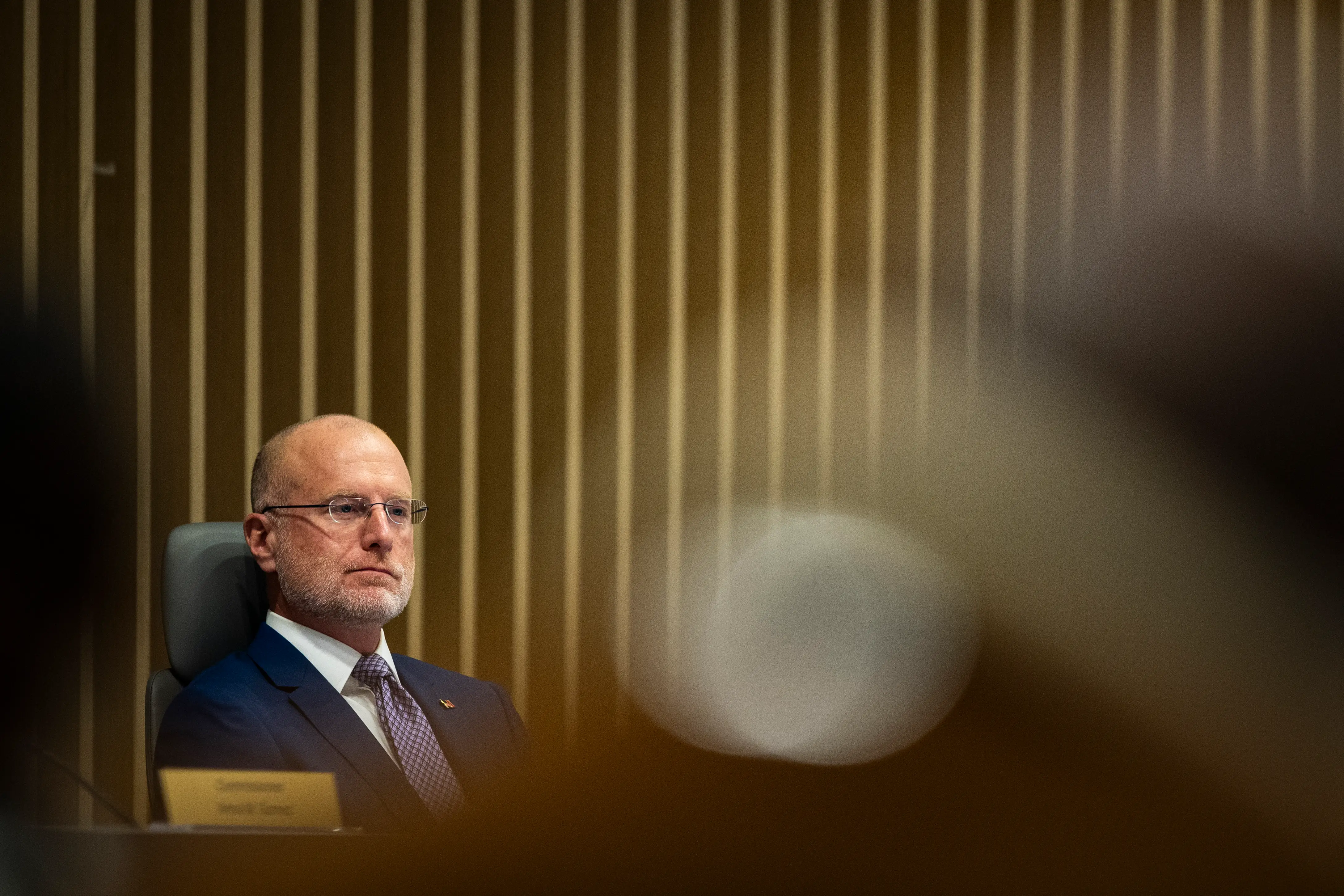 FCC Chair Brendan Carr sits at a desk with a serious expression.