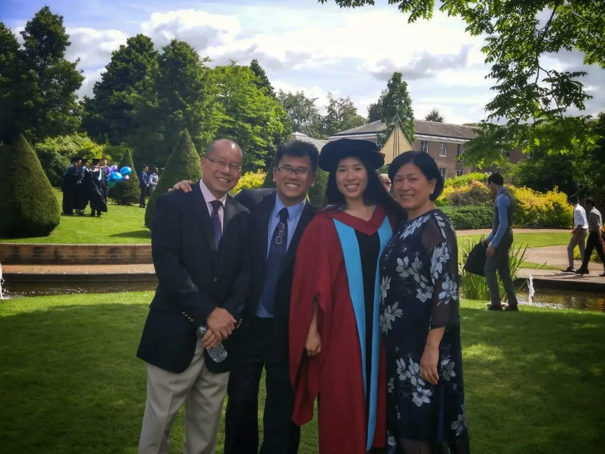 Natalie Chiu in a cap and gown with her family after graduating.