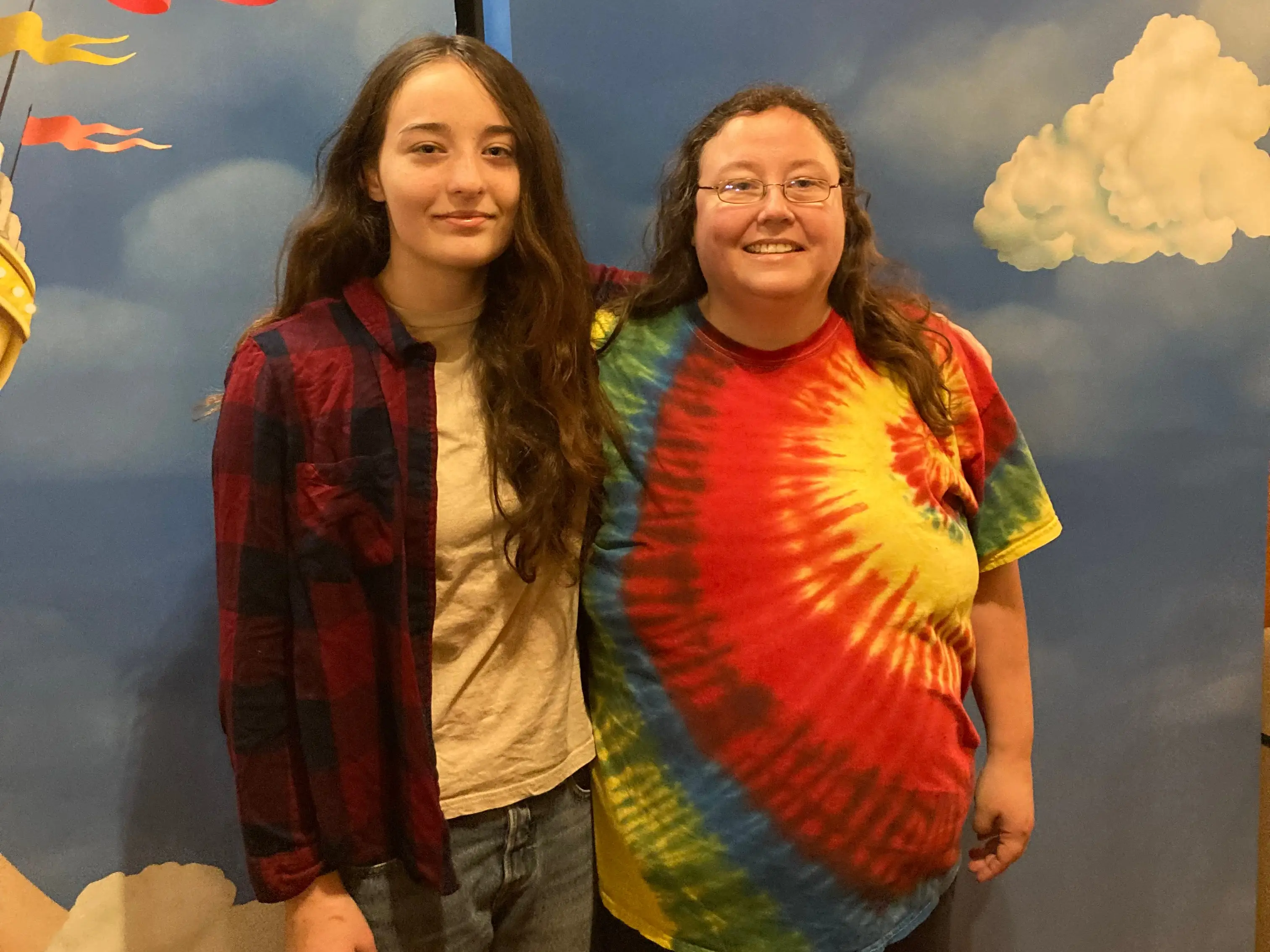 A mom and daughter standing in front of a board showing a Broadway show.