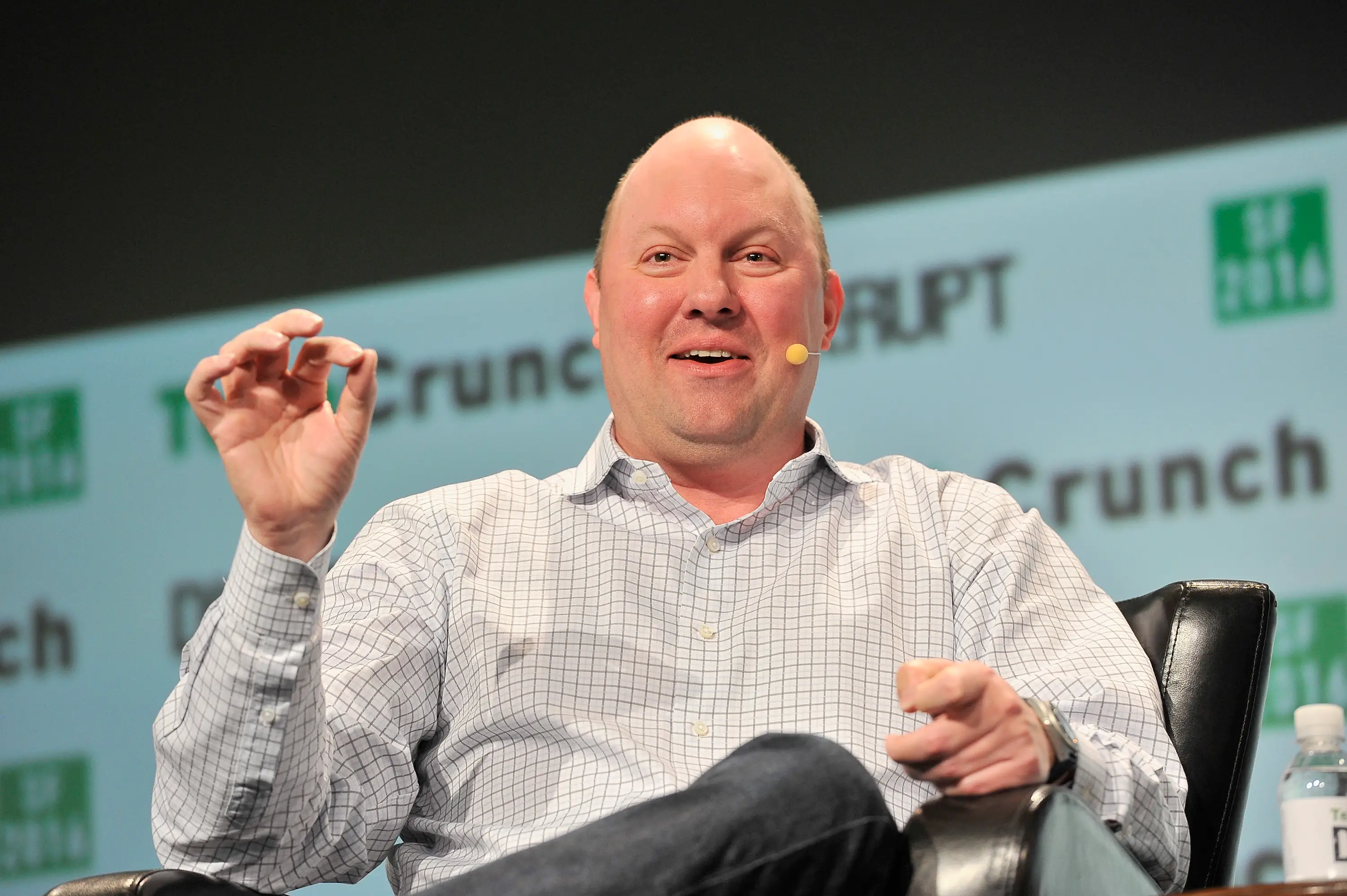 Marc Andreessen is sitting on a black leather chair onstage. He's wearing a white button-up shirt with a gray window pane pattern.