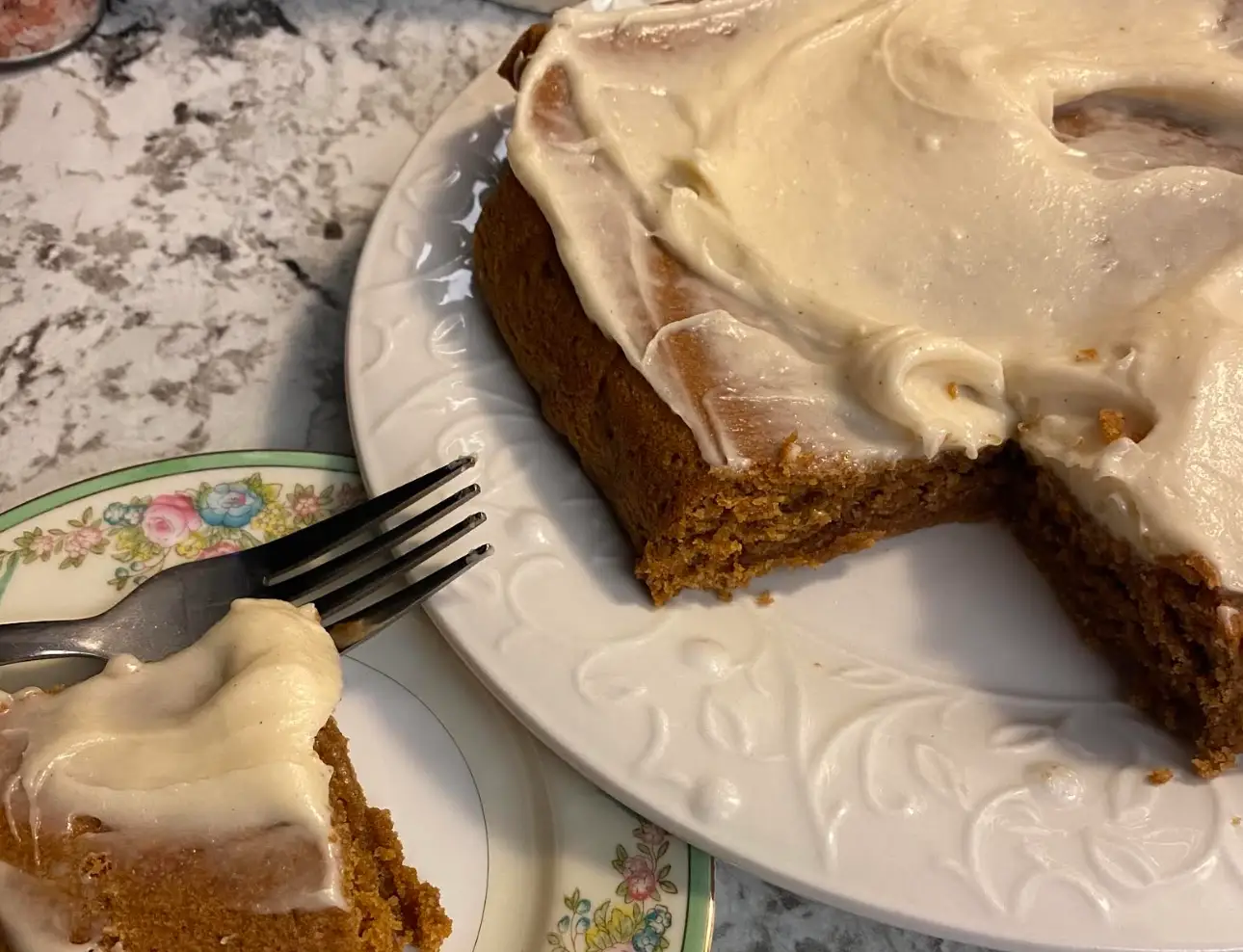 Homemade gingerbread cake with cream-cheese frosting on plates.