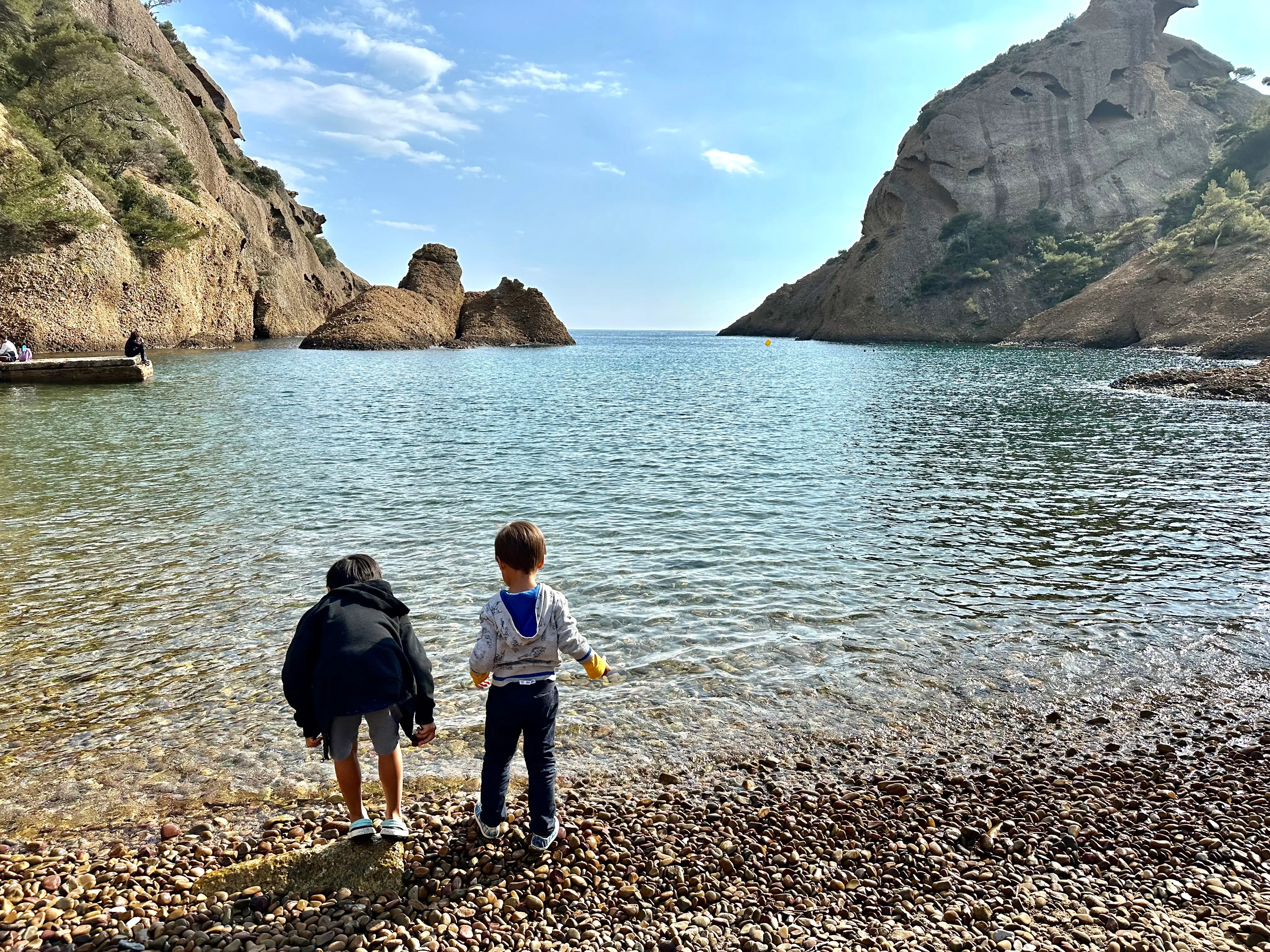 Two young boys playing on the rocks of a beach.