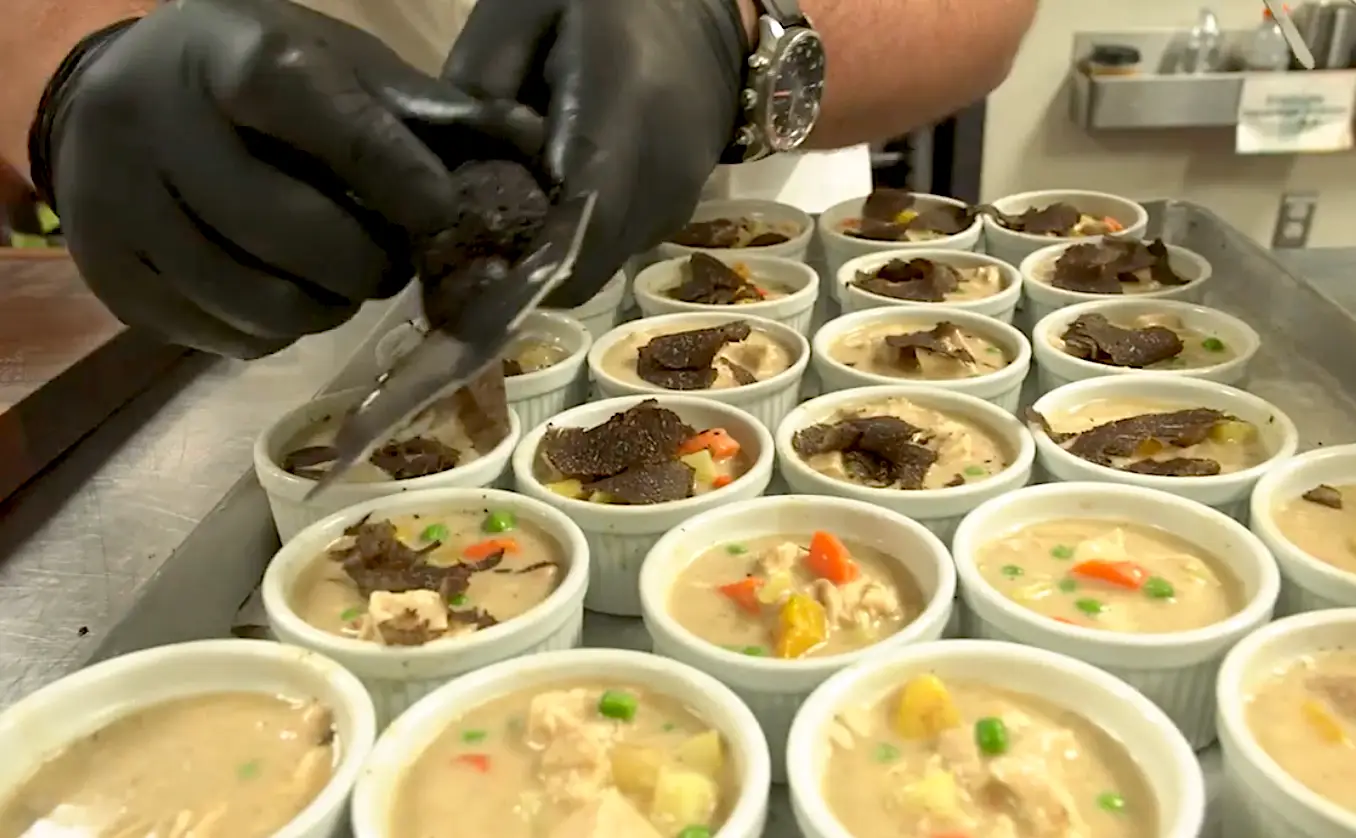 Someone shaving truffle on top of shicken pot pie.