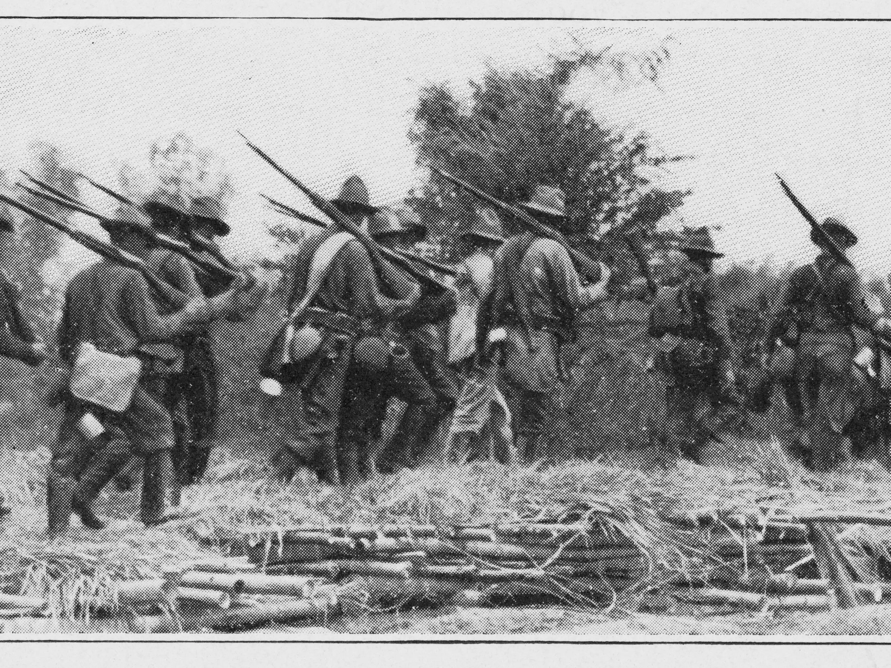 American soldiers walking in a field with rifles.
