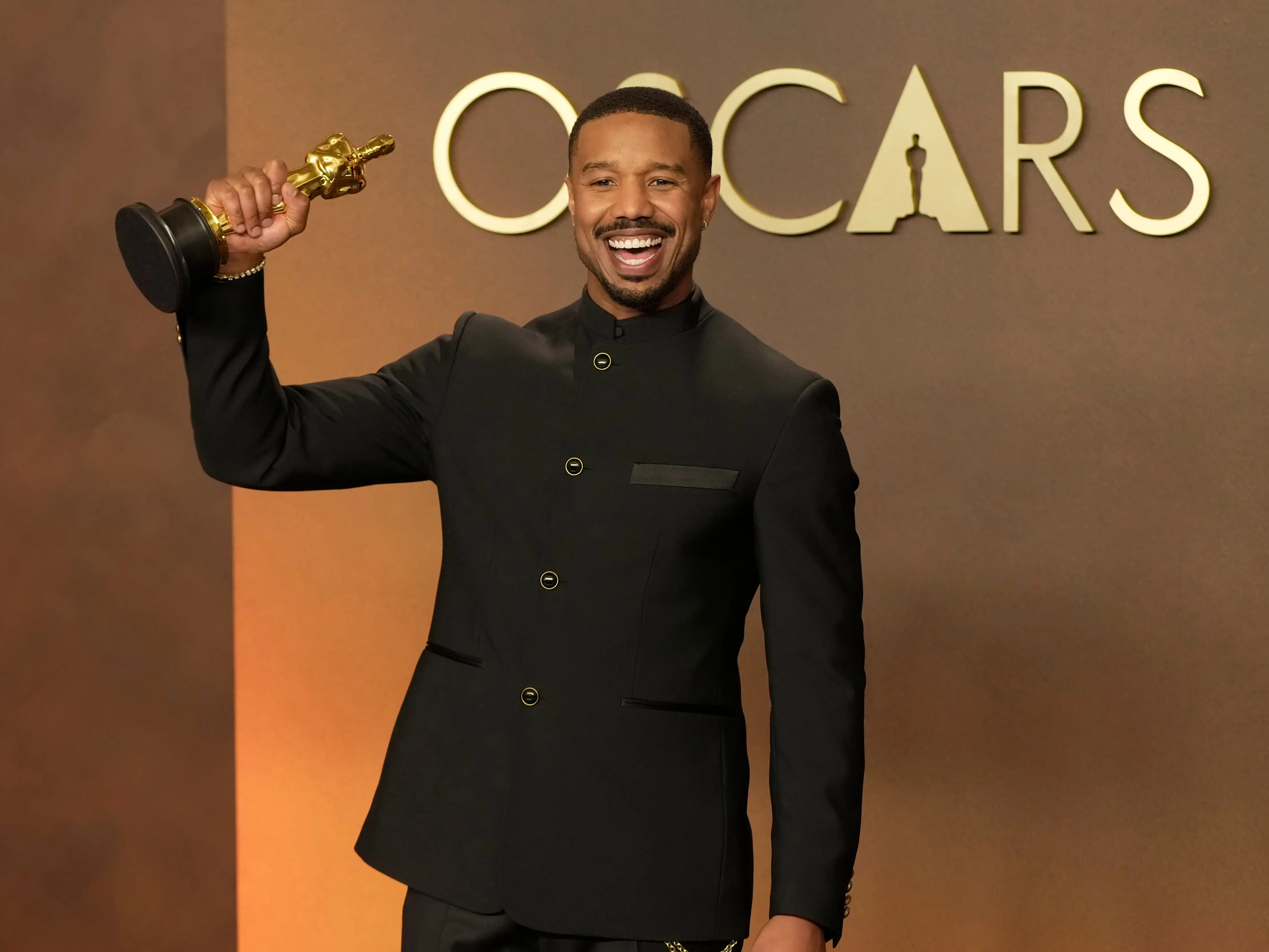 Michael B. Jordan holding up his statuette at the Oscars,