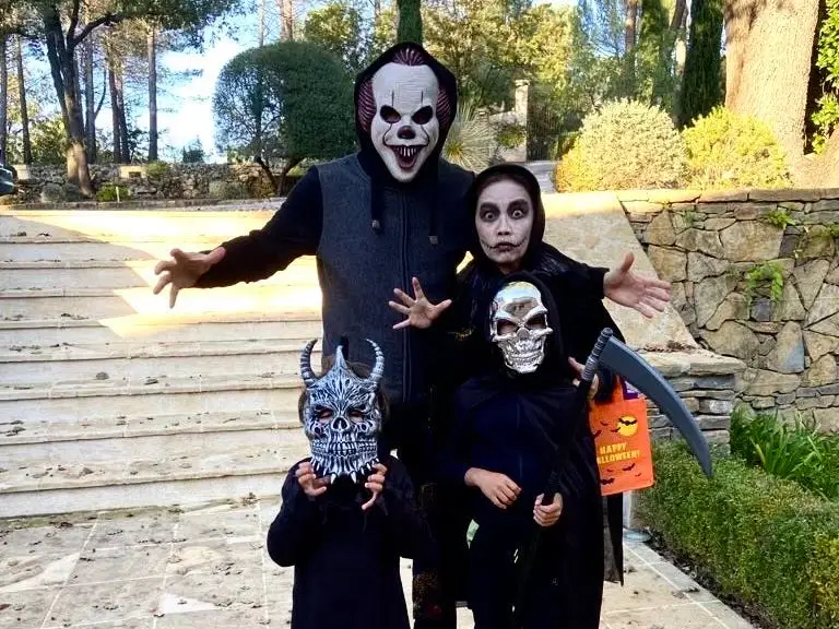 A man, a woman, and two young children dressed up in masks and face paint for Halloween.