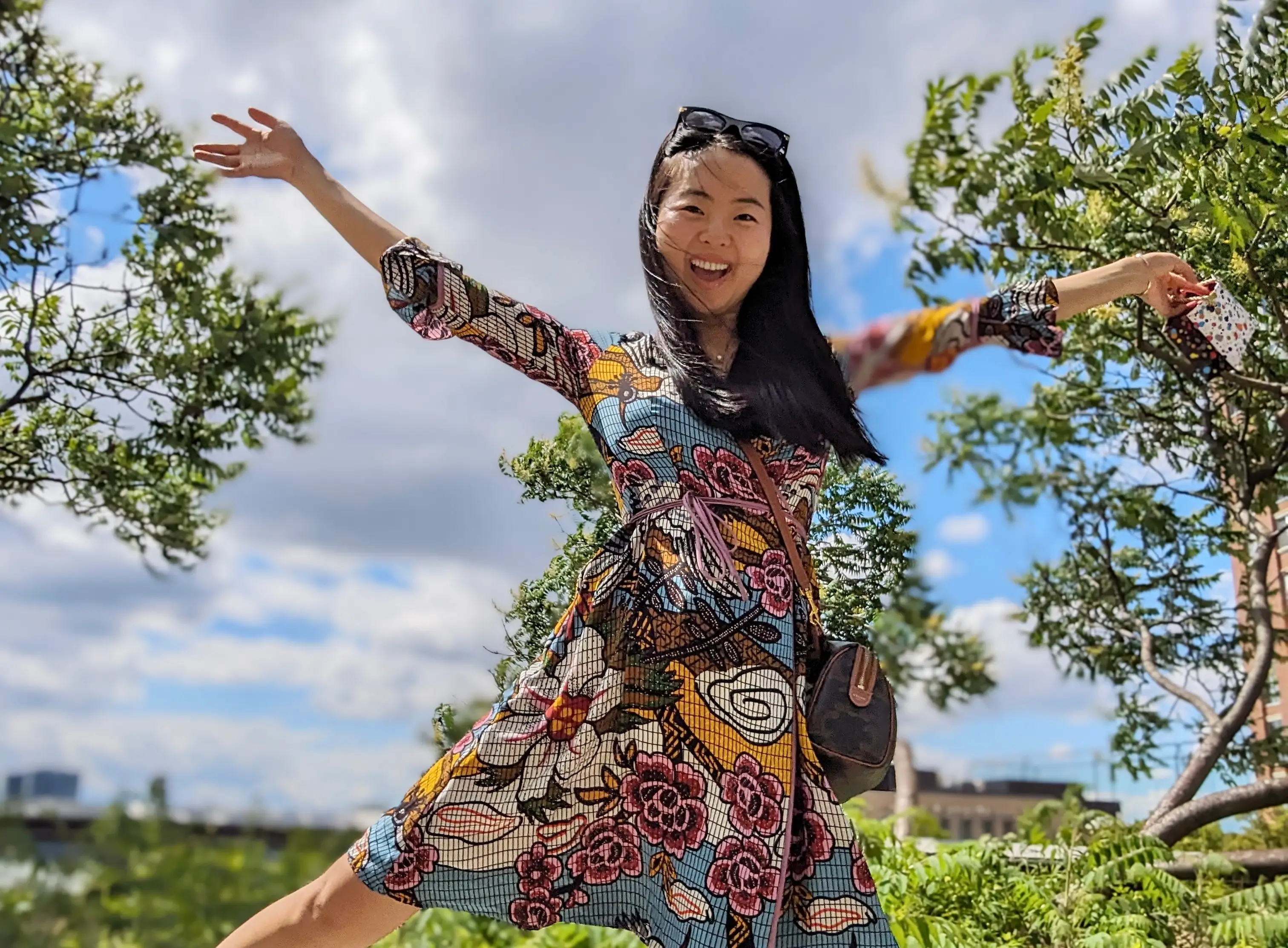 Woman in colorful dress smiling with arms outstretched