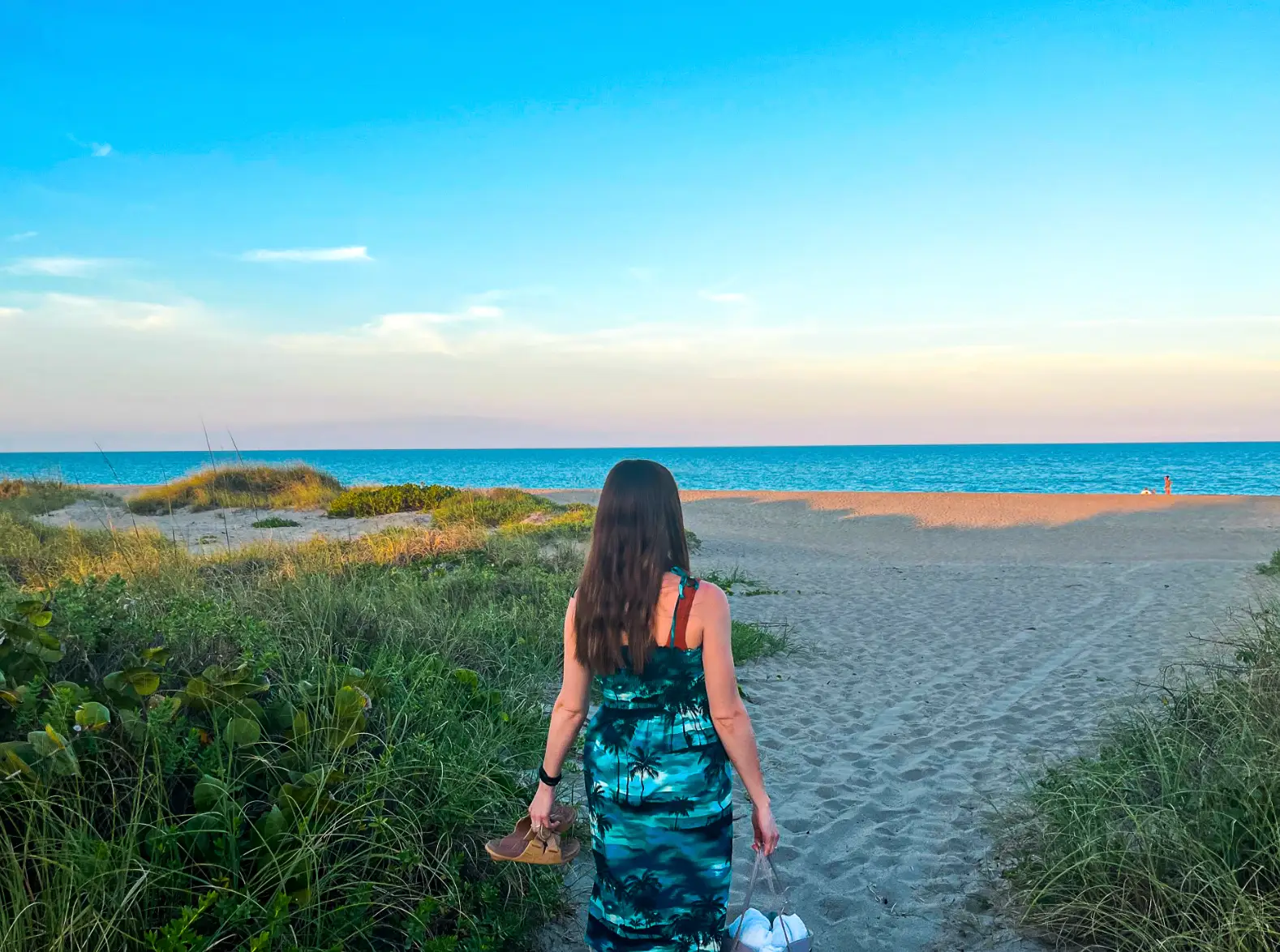 The writer carrying her shoes and a bag onto a quiet beach in Fort Pierce, Florida.