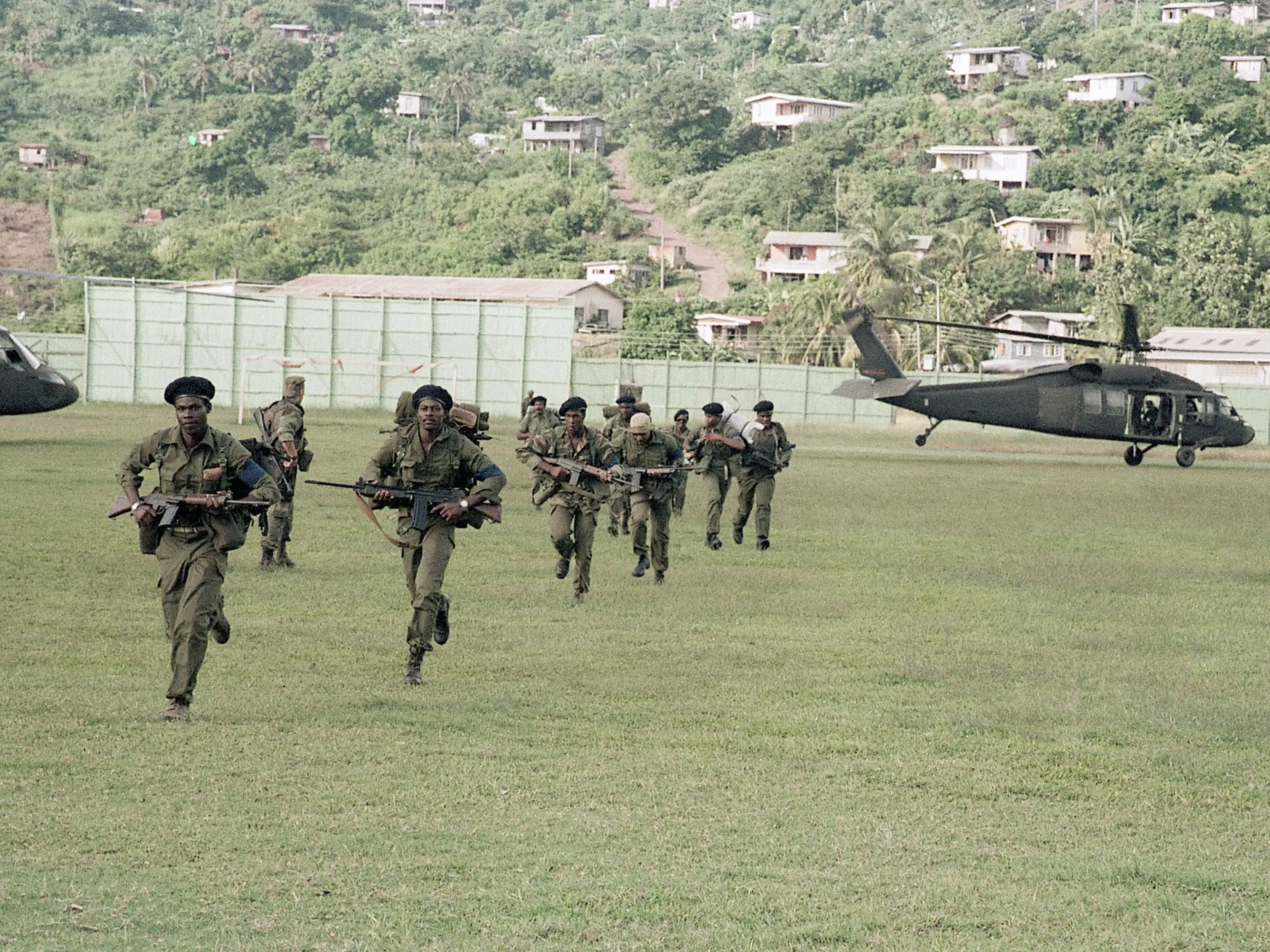 US soldiers run across a soccer field.
