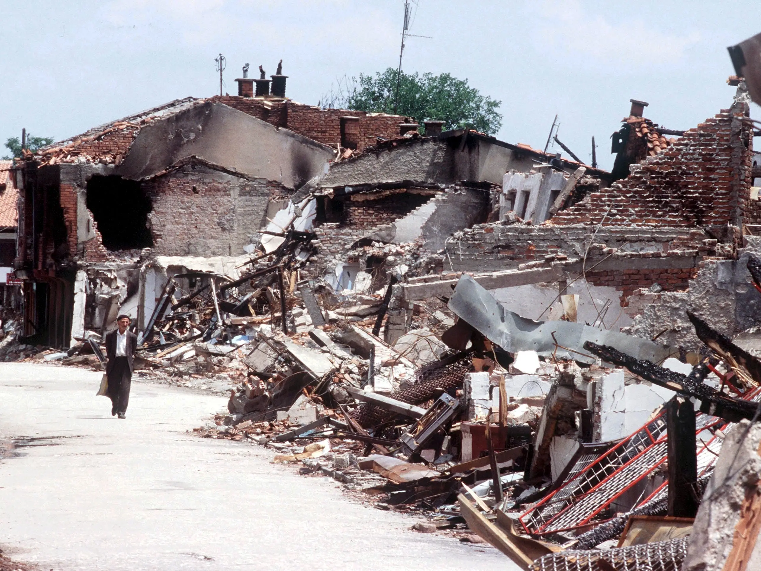 A Kosovan civilian walks next to rubble.