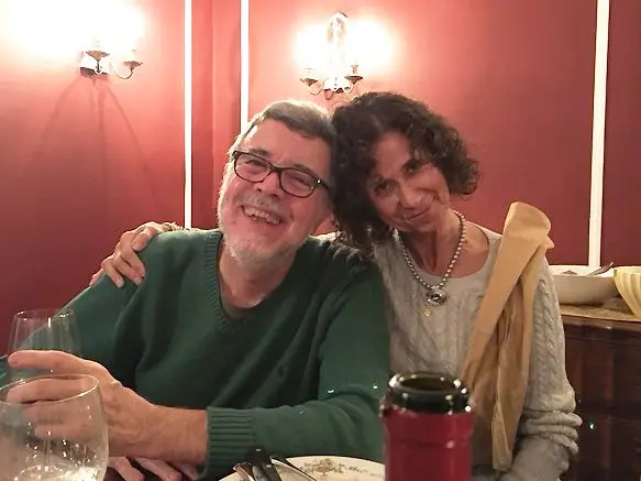 An older couple sitting at a restaurant with red walls.