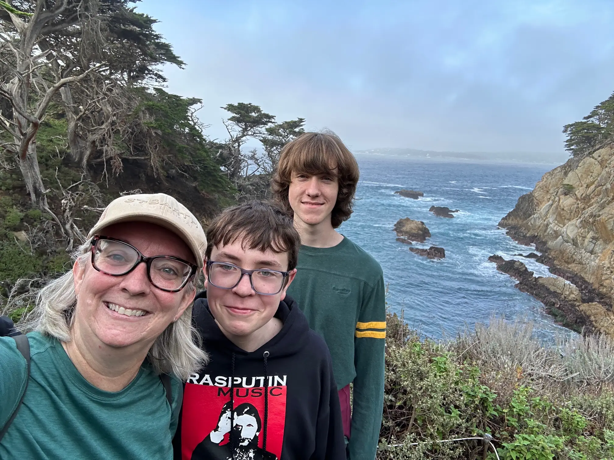 The author poses on a cliff overlooking water with two of her children.