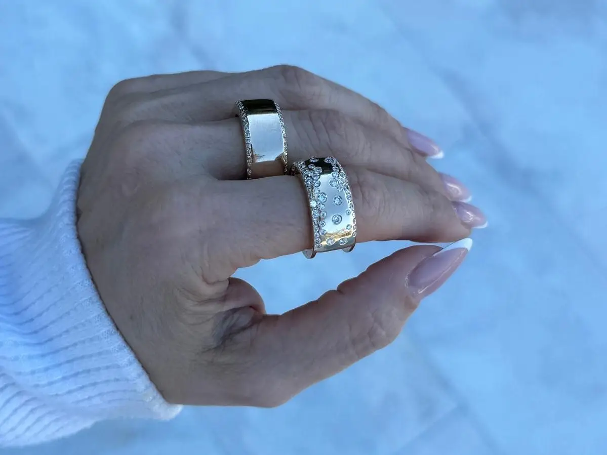 Manicured hand with two Oura Rings with diamond-encrusted jackets adorning them.