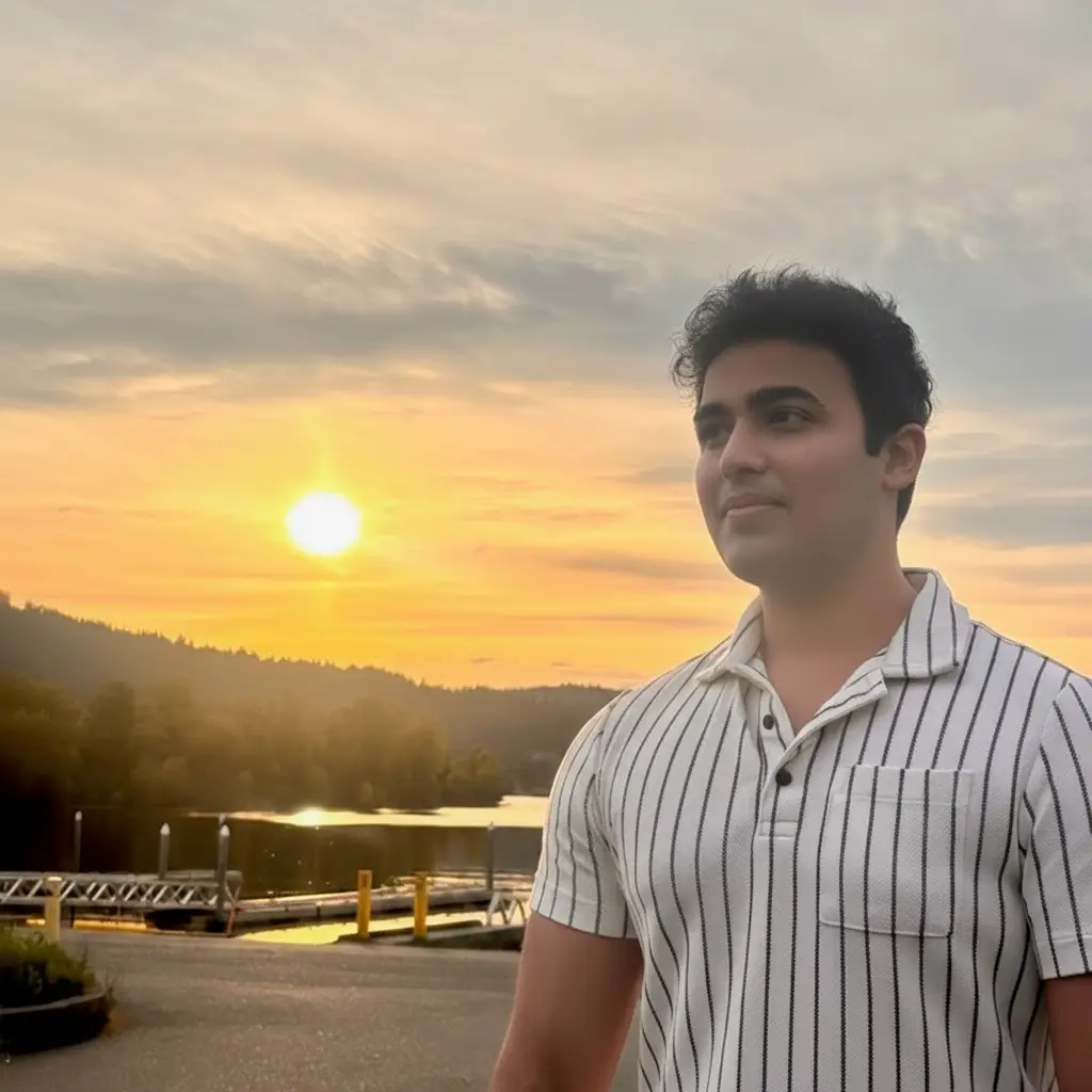 Kanav Bhatnagar is standing outdoors with a view of the sun setting behind him.