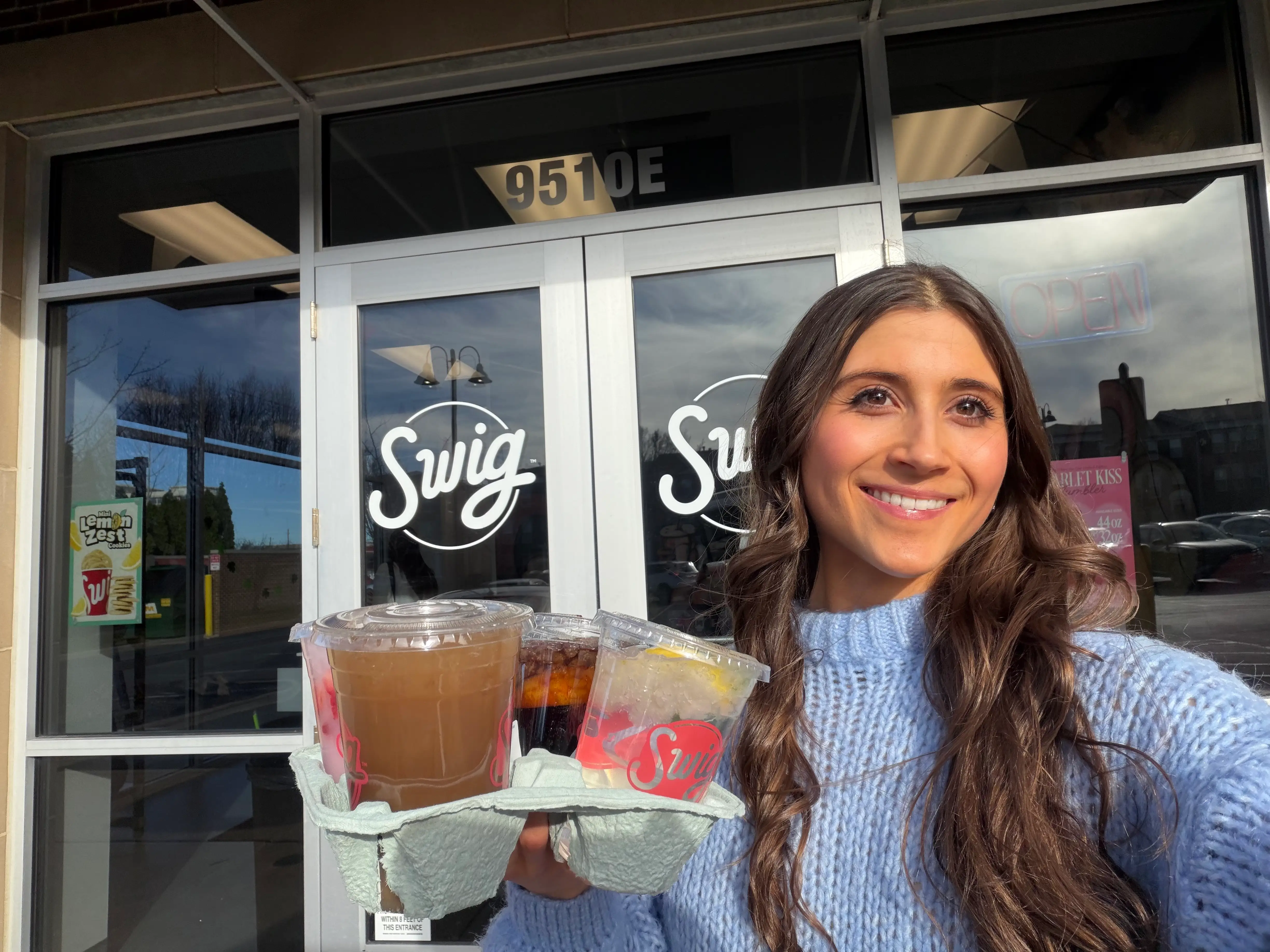 Woman holding Swig drinks in holder in front of Swig