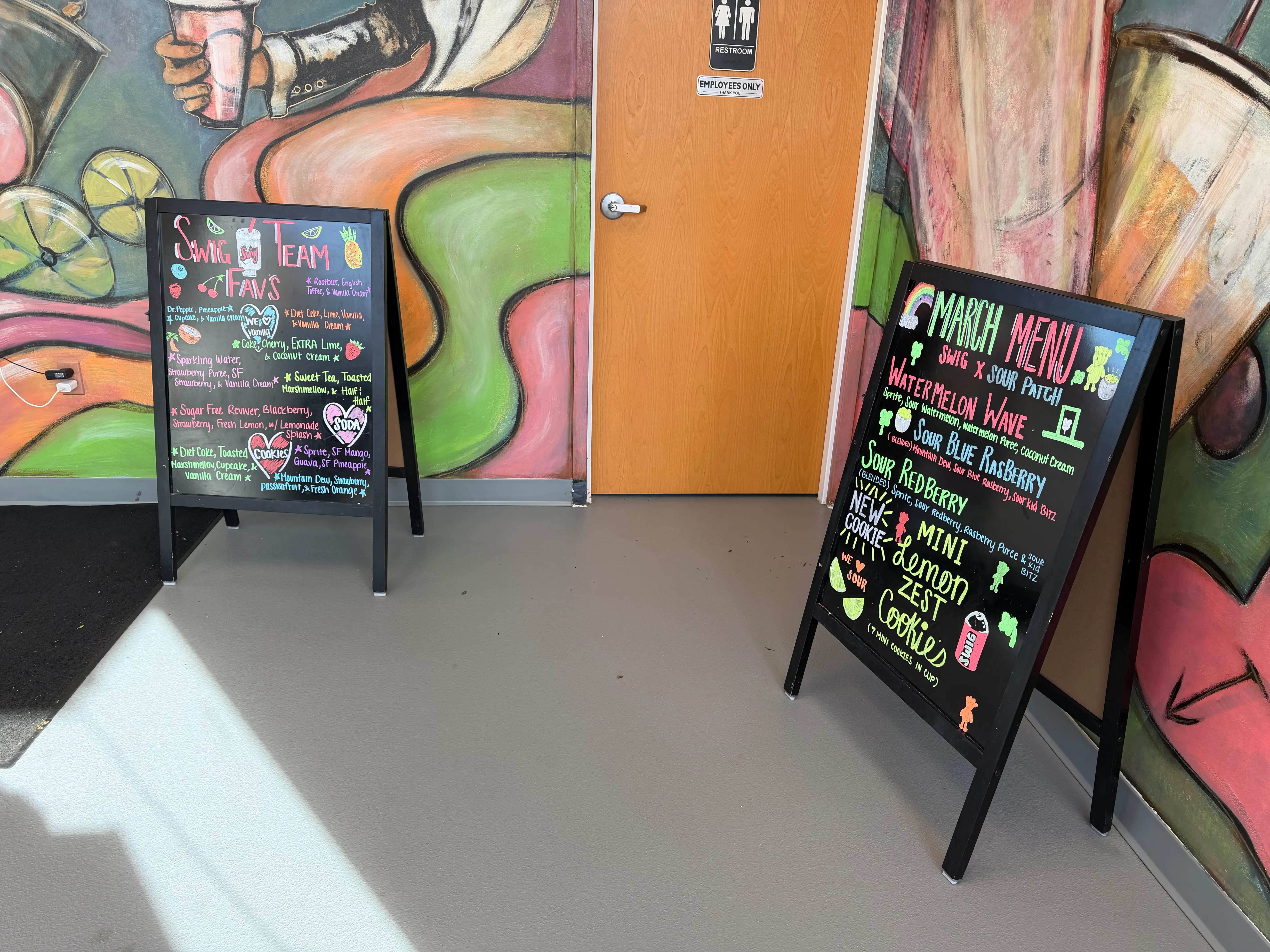 View of two standing black menus with neon lettering and bathroom door between them