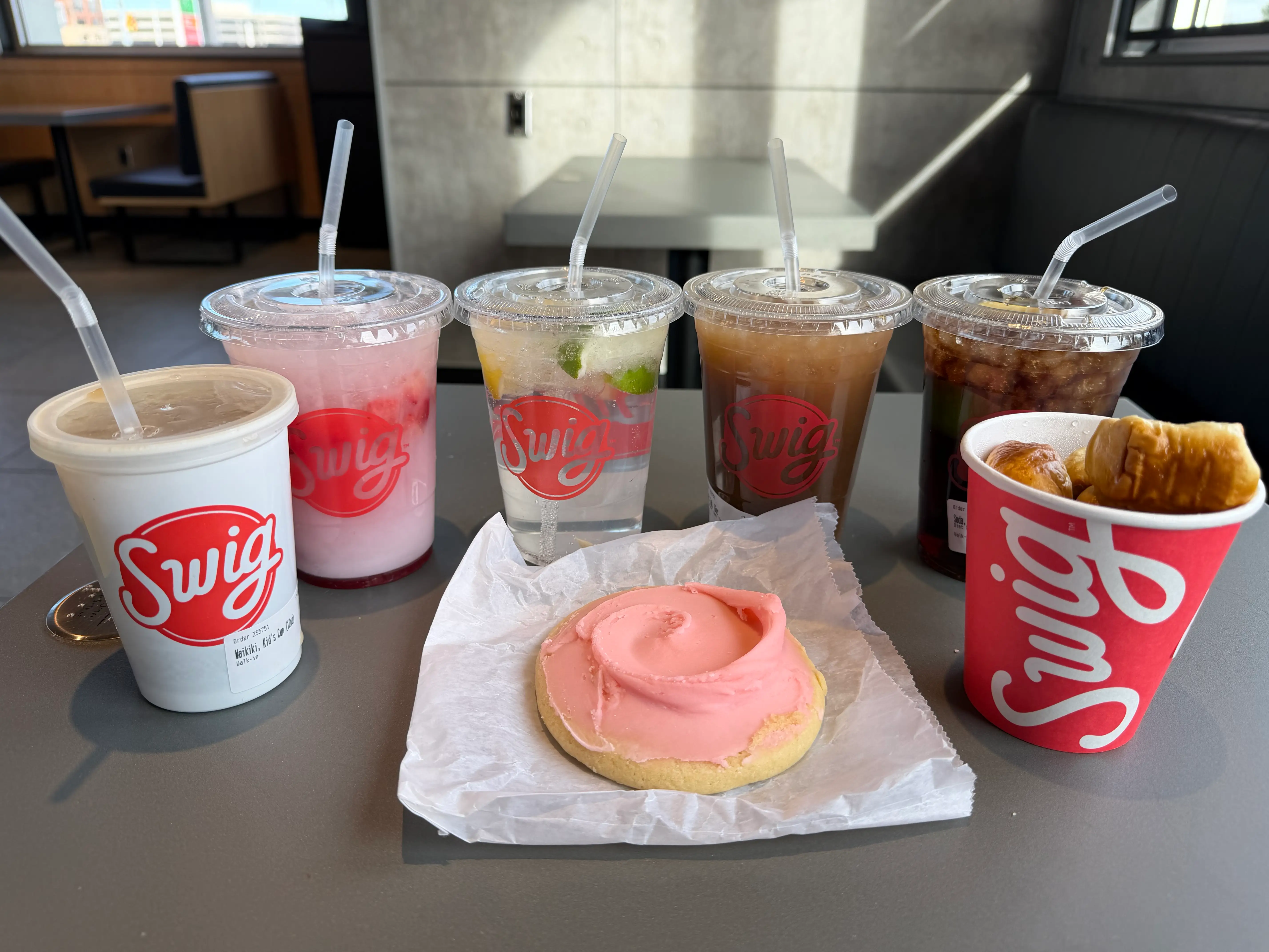 Swig drinks and cups surrounding a cookie on table
