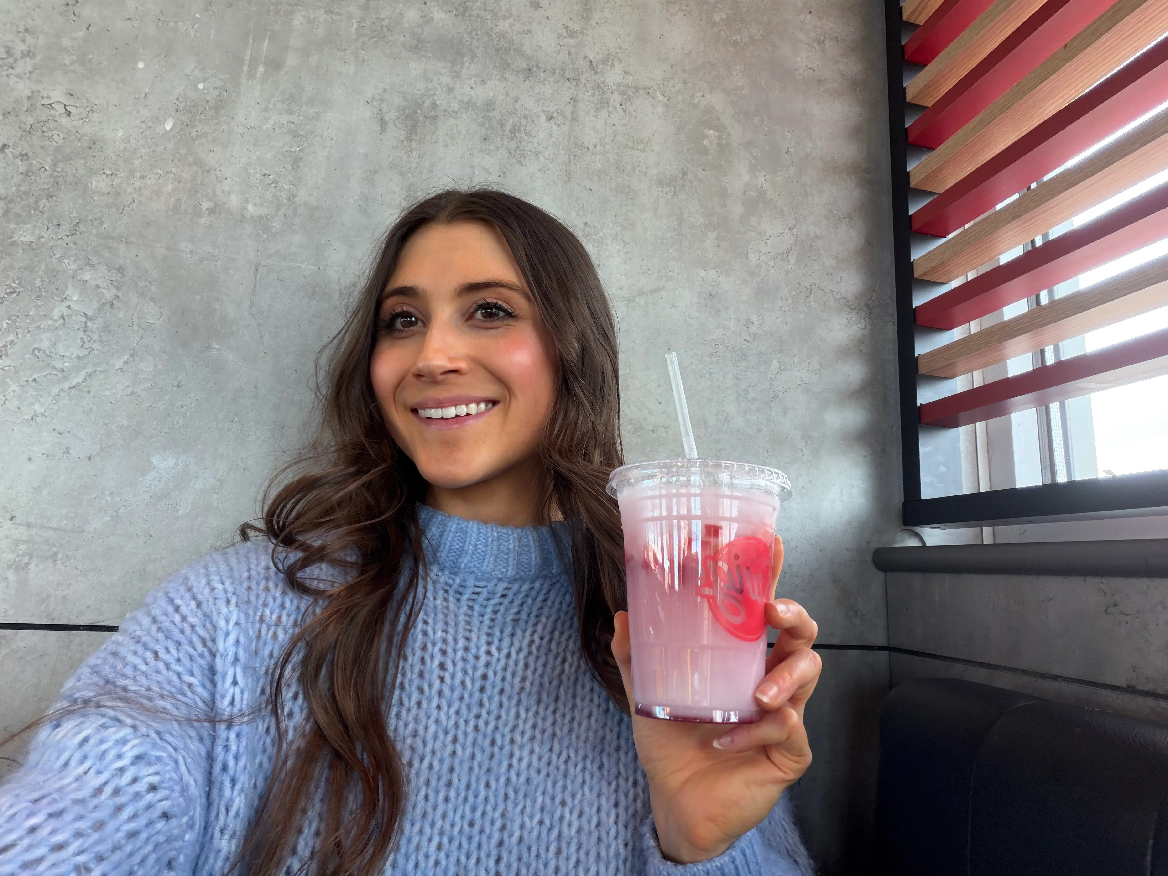 Author Savannah Born holding strawberry Swig drink, smiling