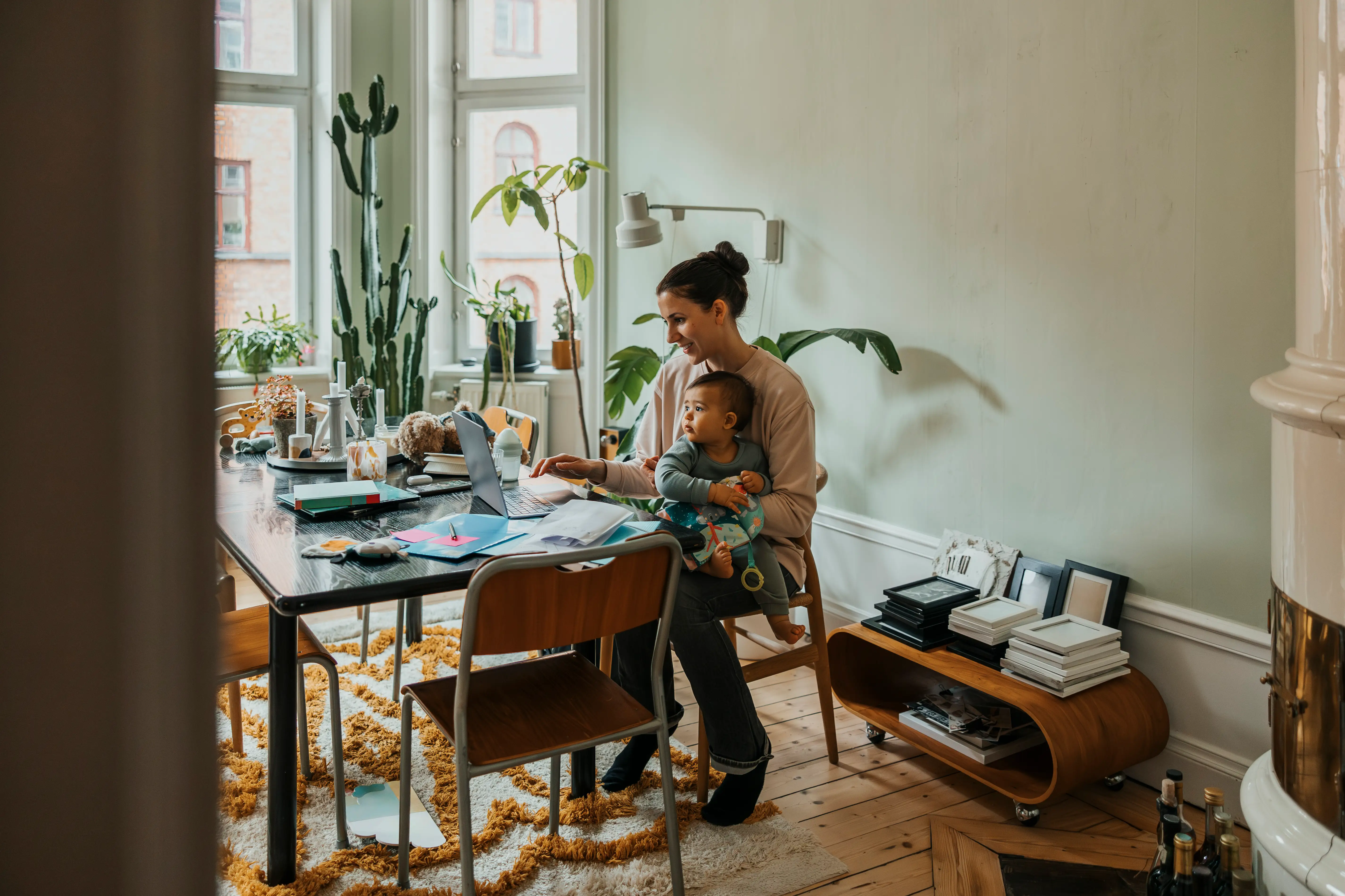 a mother working at a table with a baby in her lap