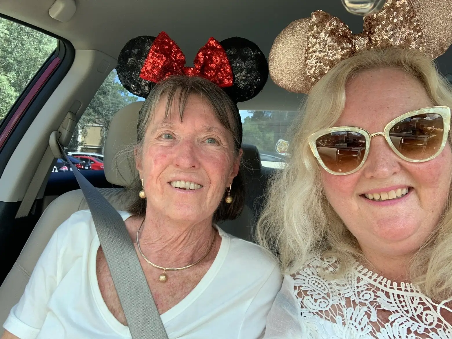 Two women in a car wearing Mickey Mouse ears.