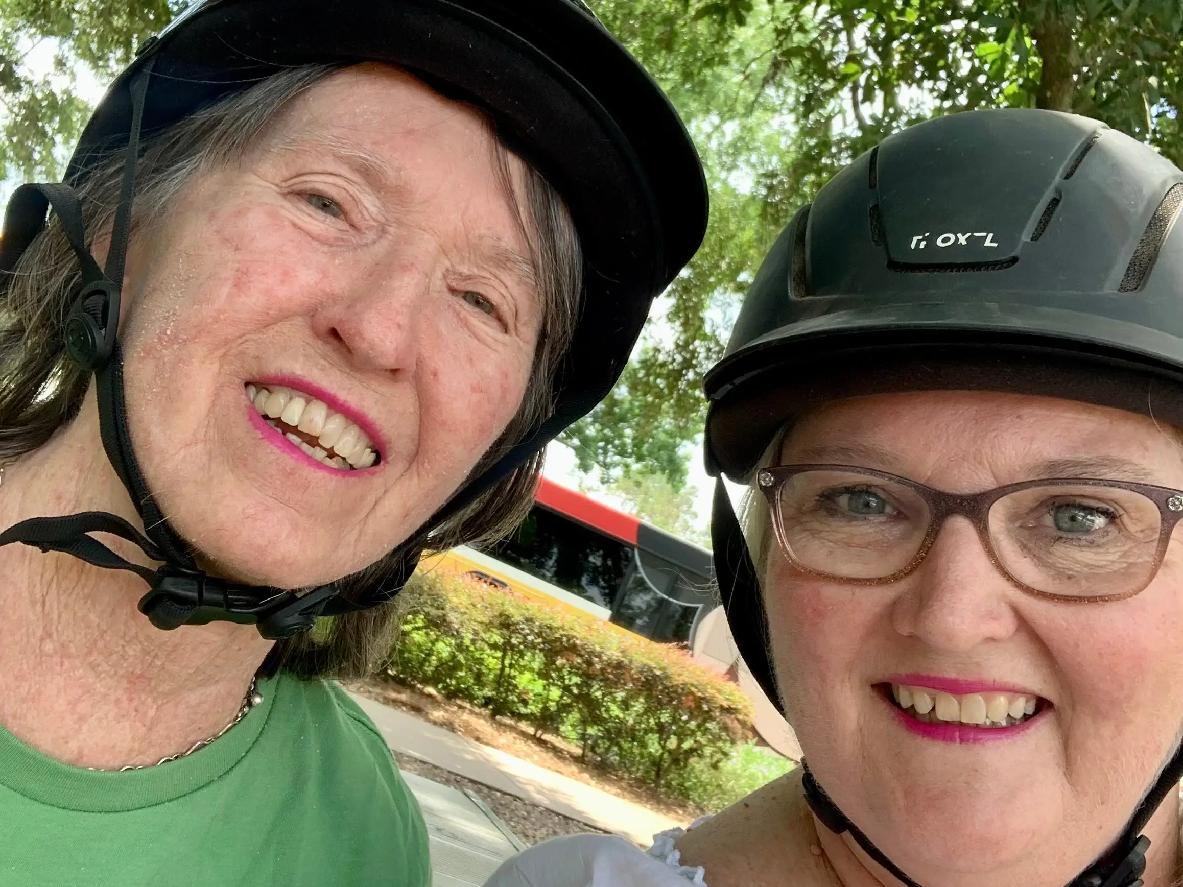 Two women wearing bike helmets take a selfie.