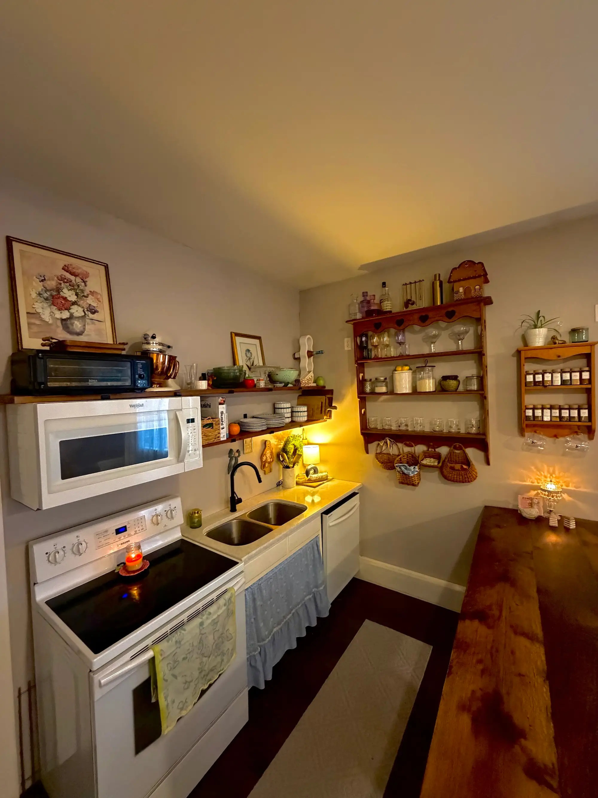 A kitchen with a wood island and wood open cabintry hanging on the wall.