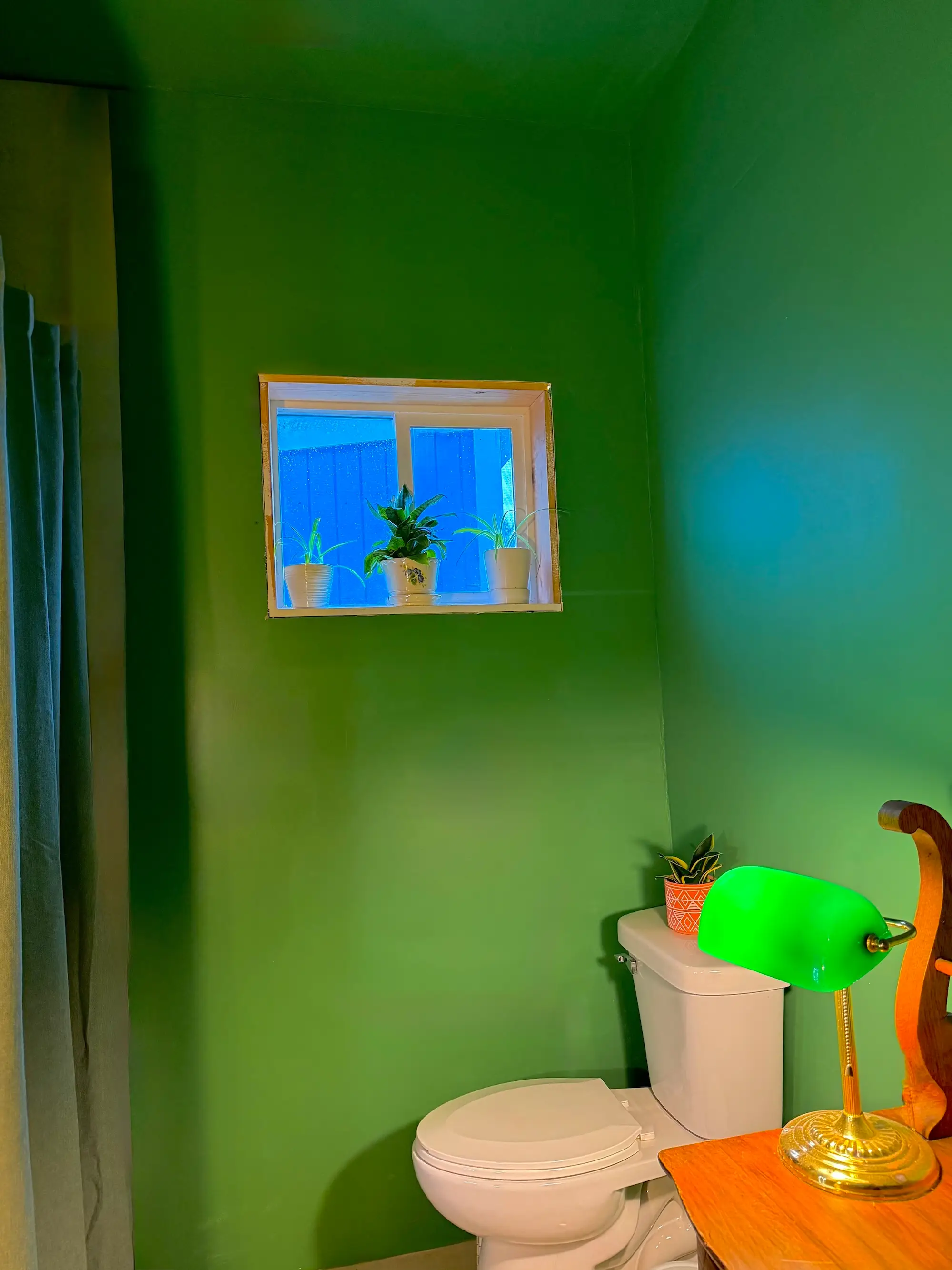 A bathroom with green walls, a toilet, and a shower,