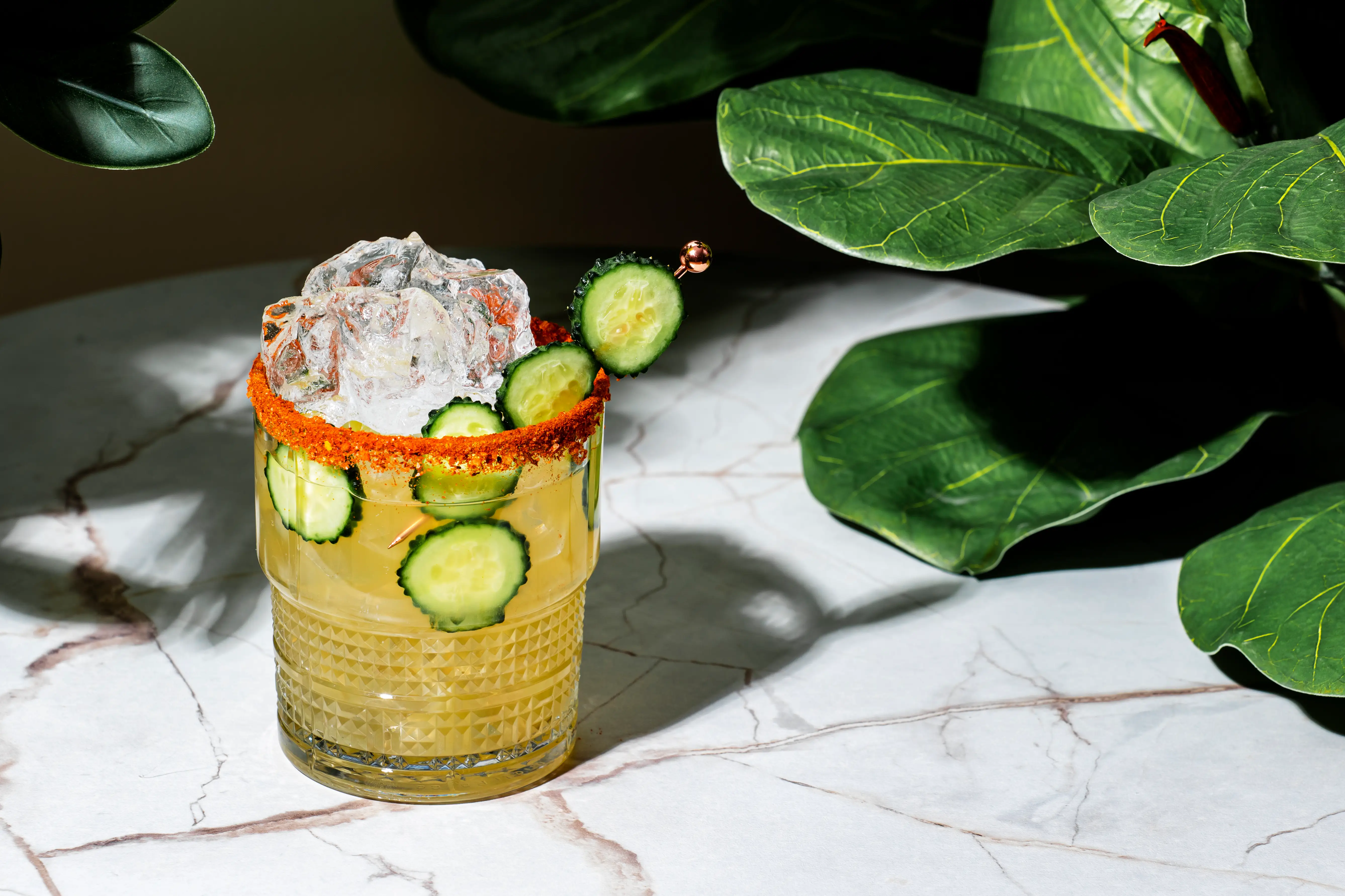 Spicy margarita on marble table near leaves
