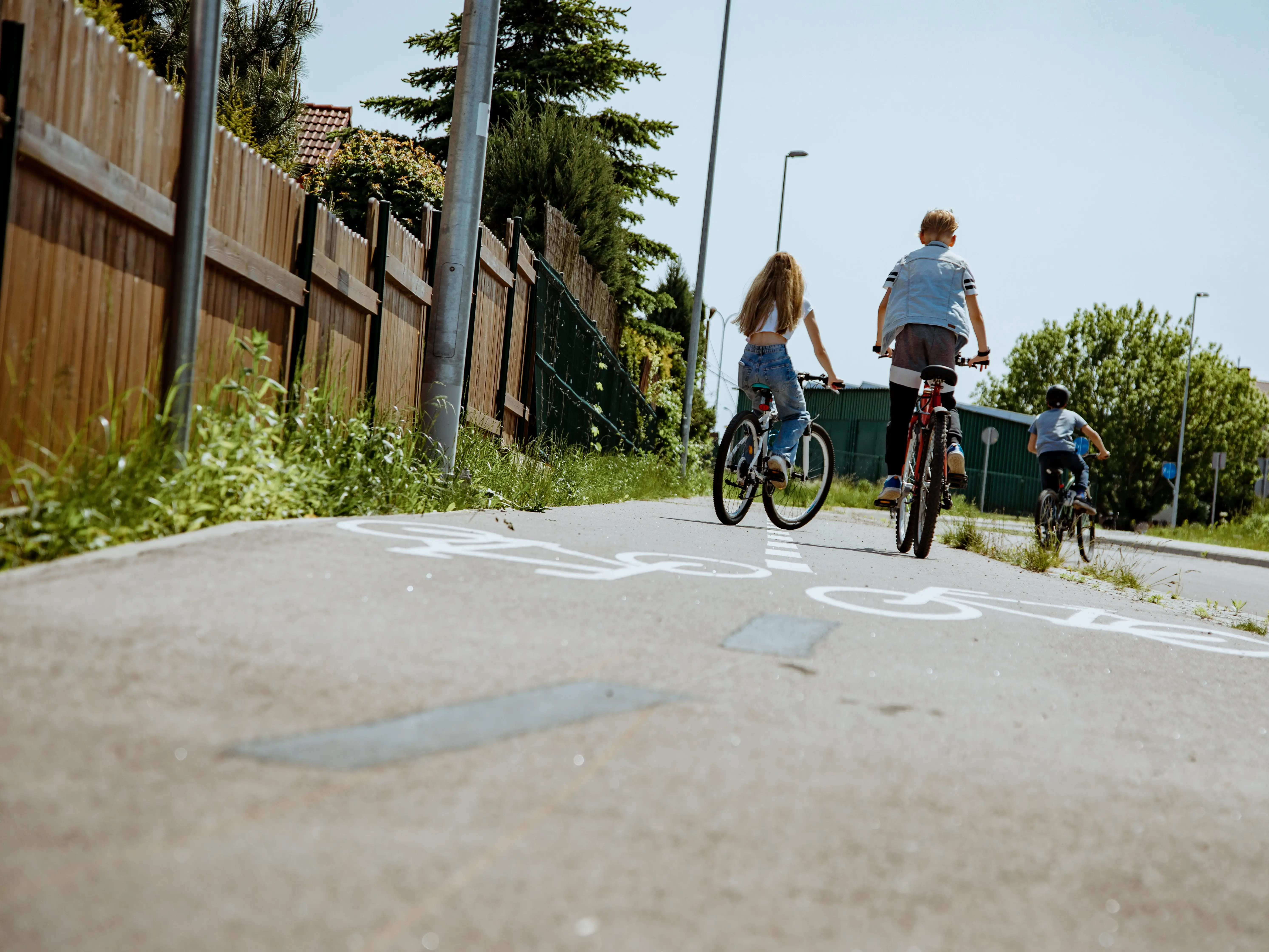 three kids riding their bikes through a neighborhood