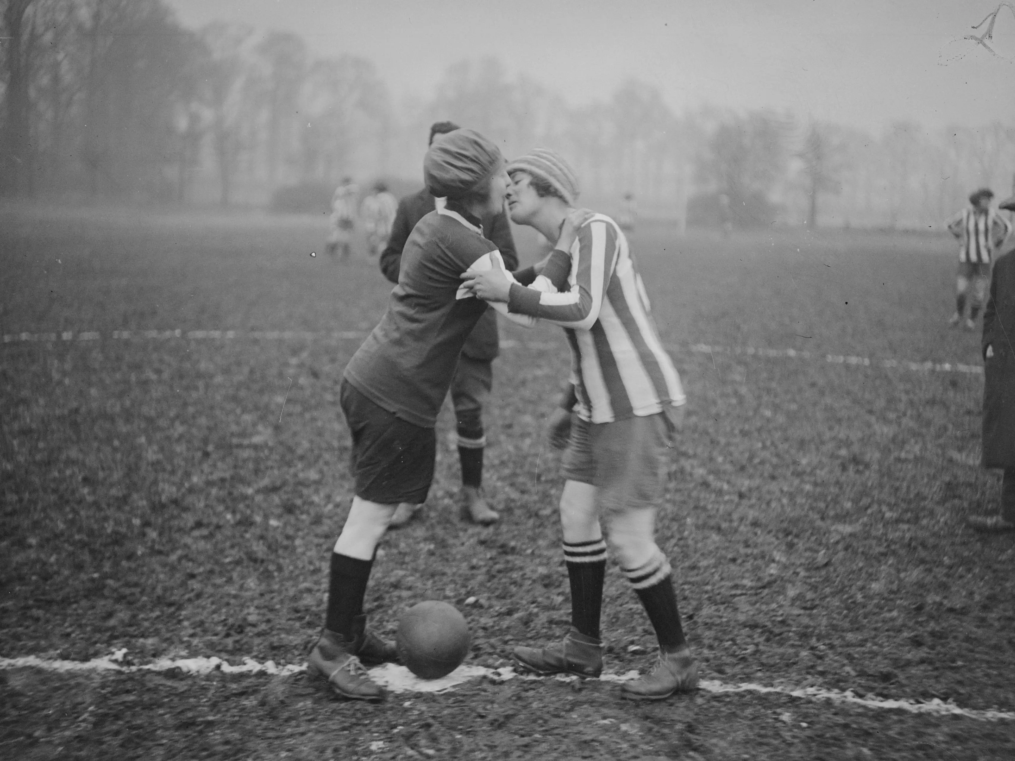 Two women kiss before a soccer match.