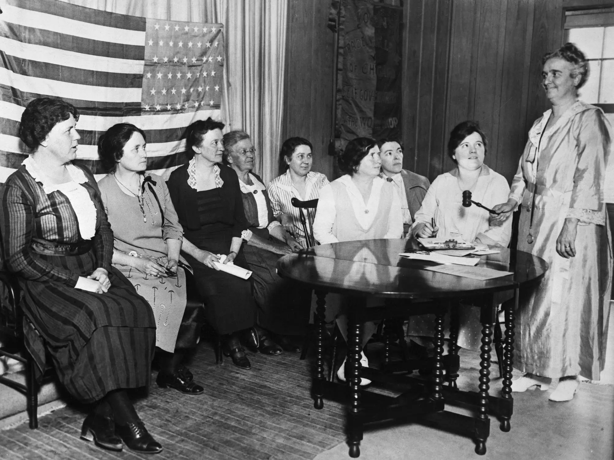 A meeting of the National Women's Trade Union League in front of an American flag.