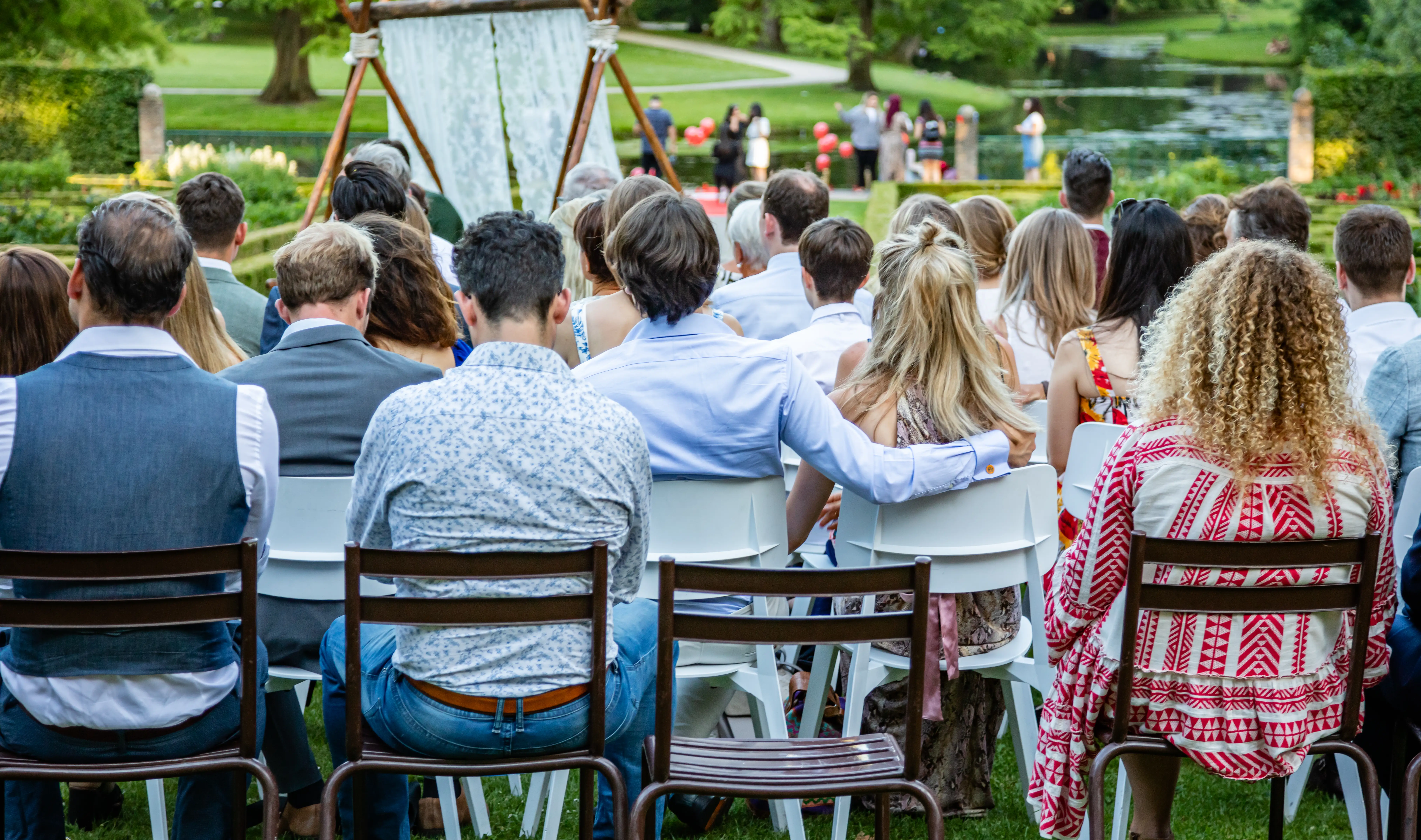 Back of people sitting in chairs at outdoor wedding