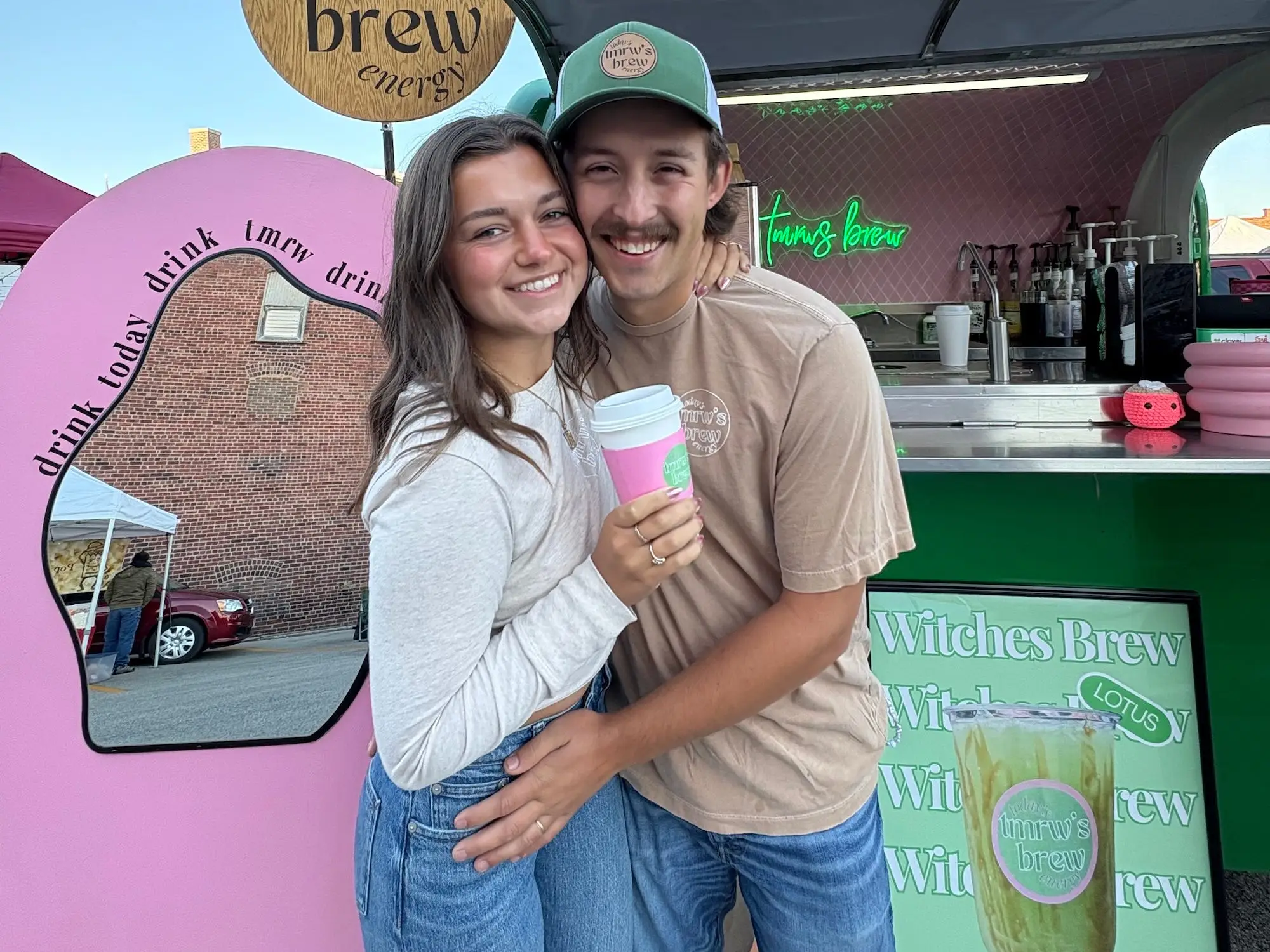 A couple embraces and stands in front of a coffee truck called 