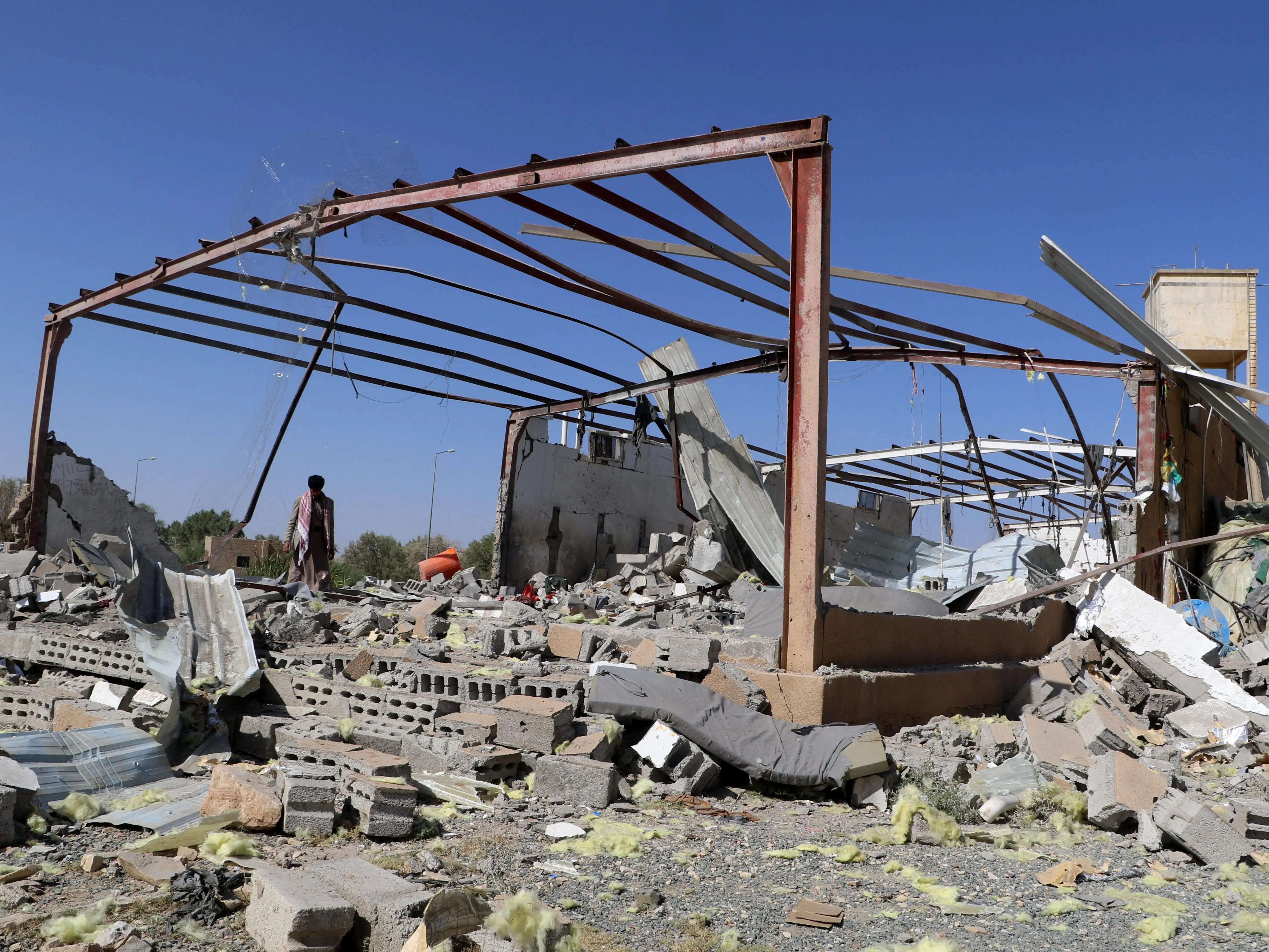 A Yemeni man walks among the rubble of a destroyed building.
