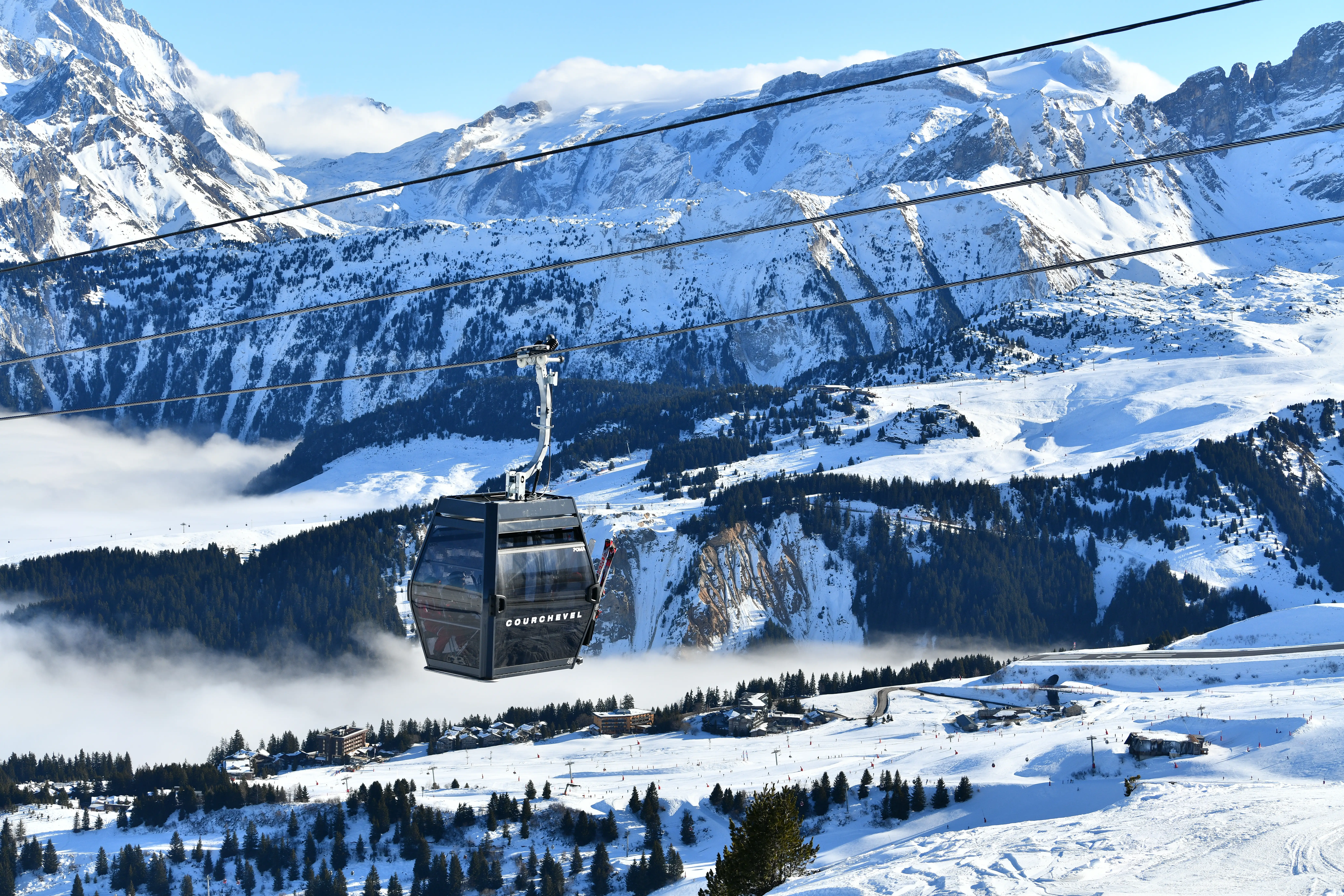 Ski lift in ski resort by winter over the snowy slopes of Courchevel town, French alps,