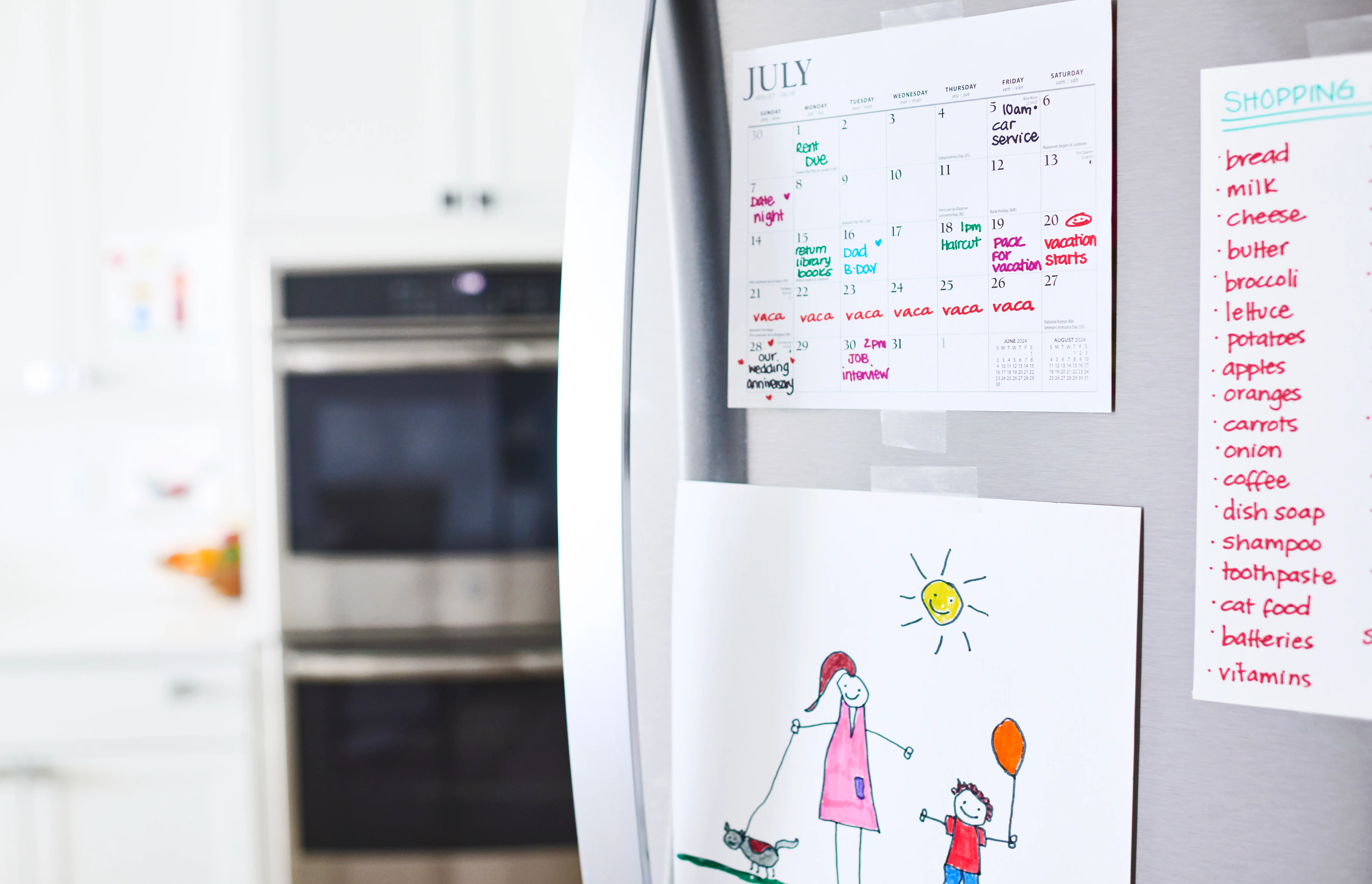 A fridge door is decorated with a picture, a calendar and a grocery list.