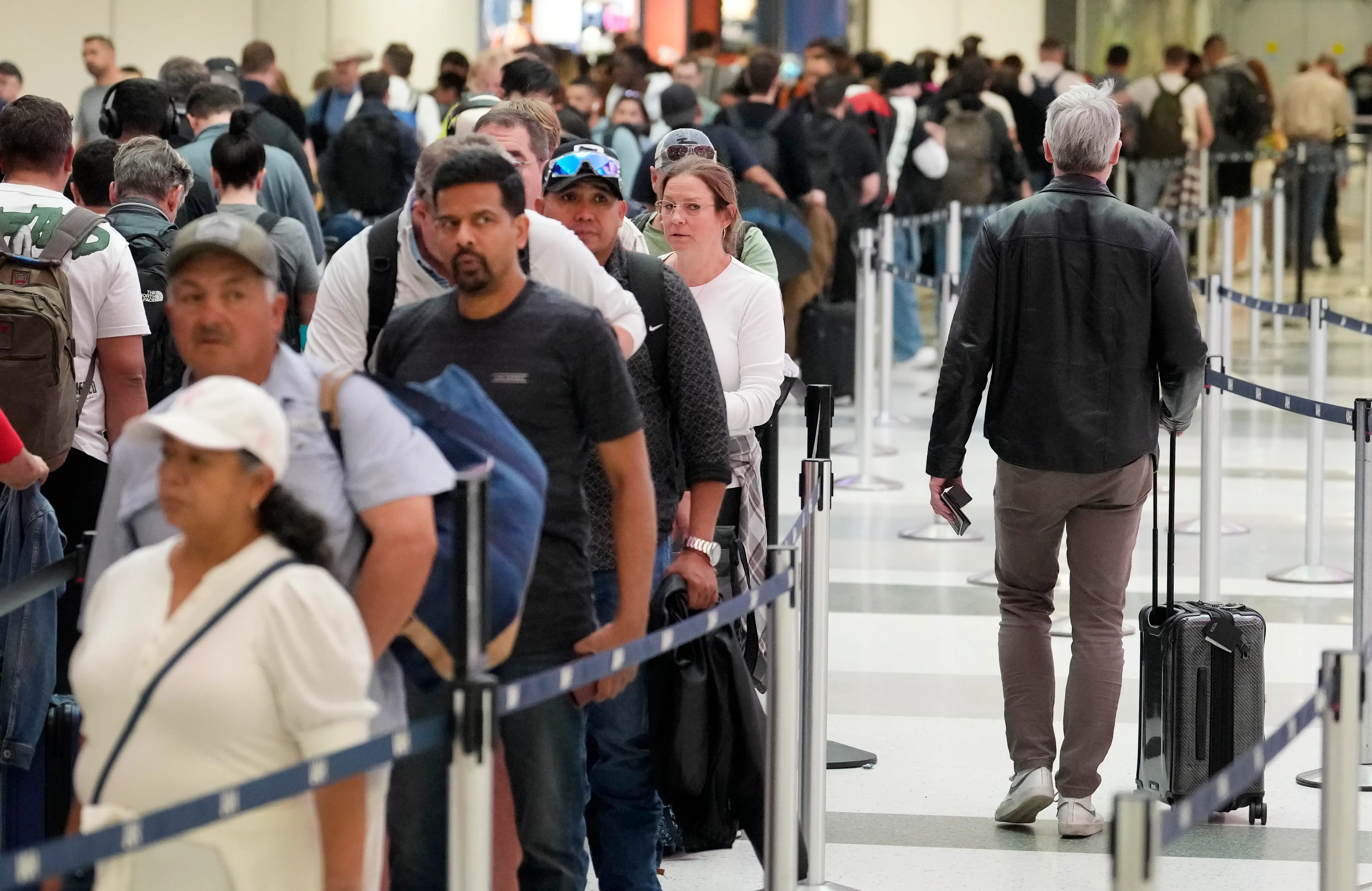 A long line of travelers waits outside airport security.