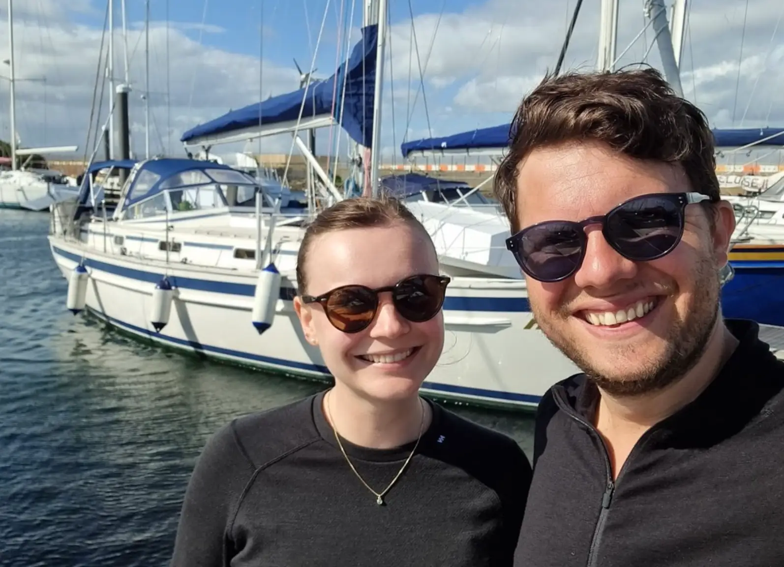 The writer and her husband standing in front of a boat in Scotland.