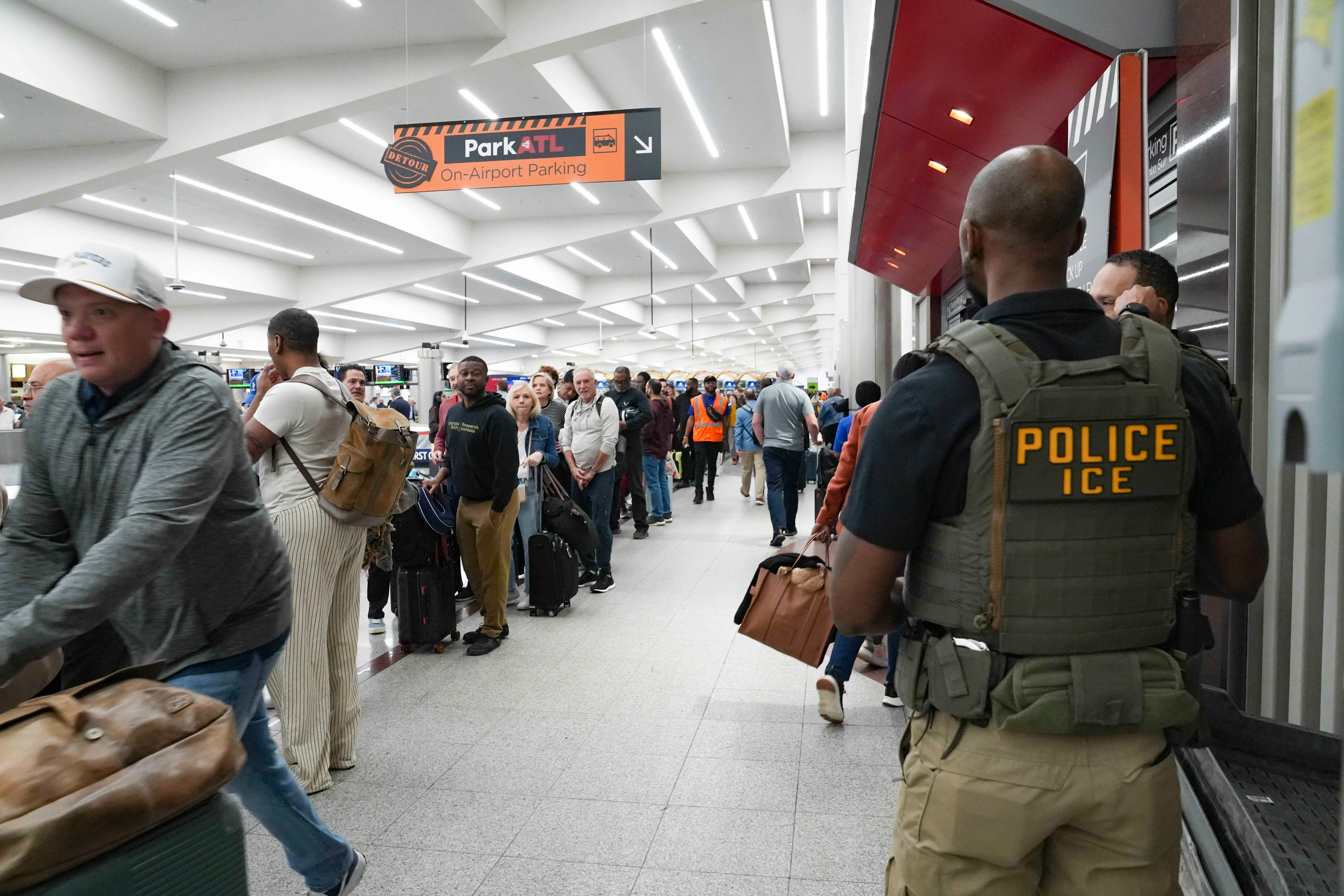 Ice agents look on as travelers stand in long lines at Atlanta Hartsfield-Jackson International Airport on March 23, 2026 in Atlanta, Georgia.