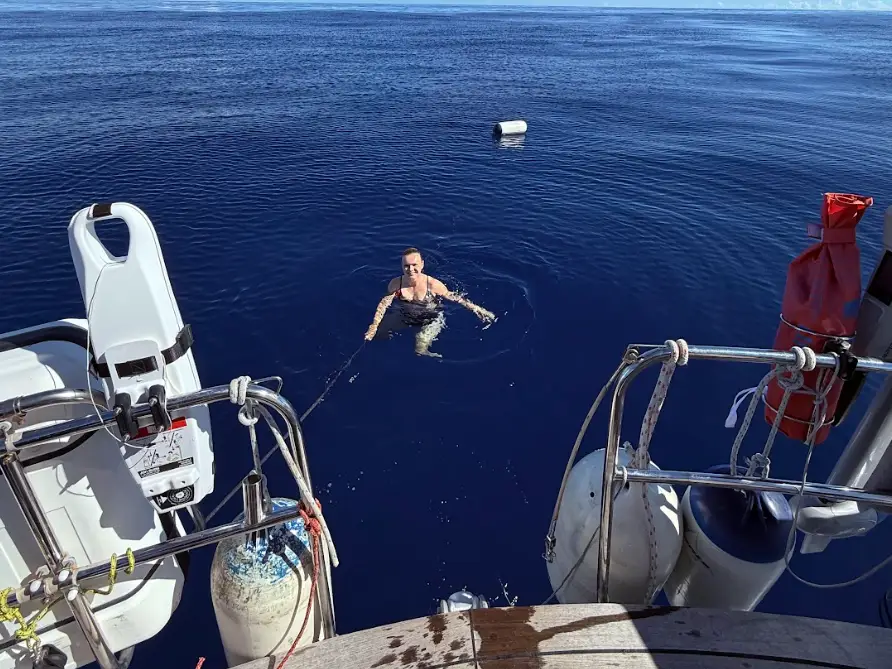 The writer swimming in the water near the boat.