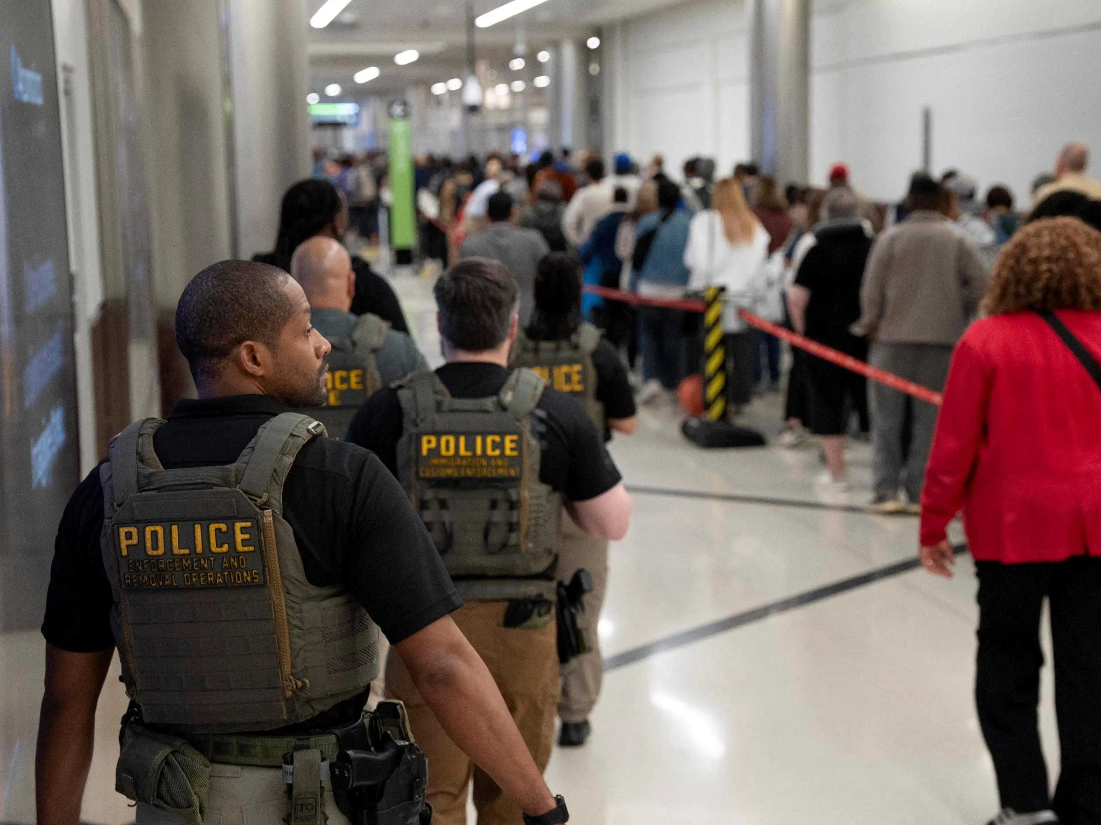 United States Immigration and Customs Enforcement (ICE) agents are present as passengers wait in line at a Transportation Security Administration (TSA) checkpoint after hundreds of Immigration and Customs Enforcement agents were ordered to deploy to airports to help fill TSA staffing gaps, at Hartsfield-Jackson Atlanta International Airport in Atlanta, Georgia, U.S. March 23, 2026.