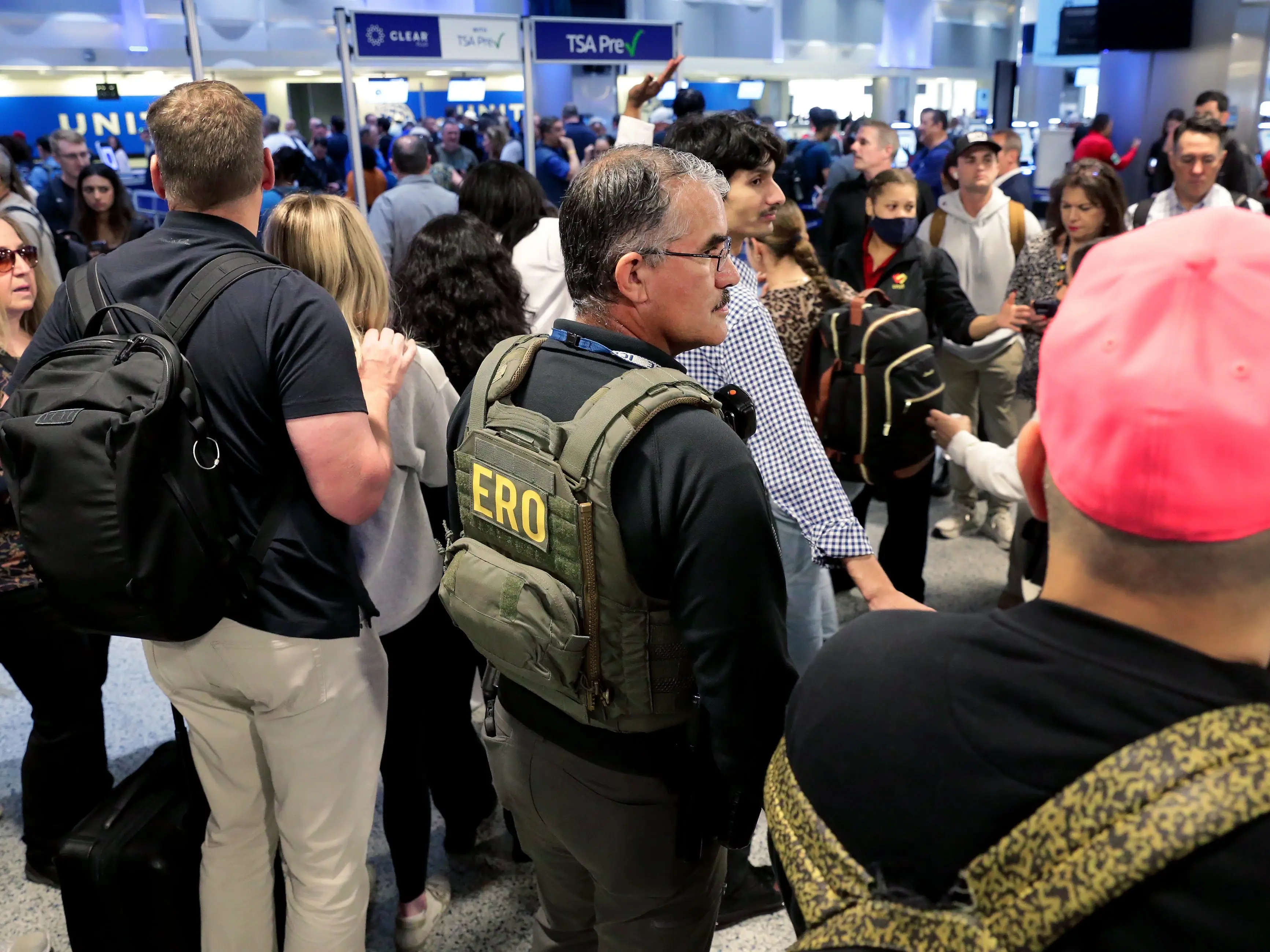A federal immigration agent stands amid air travelers to assist with security across the lines of people waiting to progress through the TSA checkpoint in Terminal C at the George Bush Intercontinental Airport, Monday, March 23, 2026, in Houston.