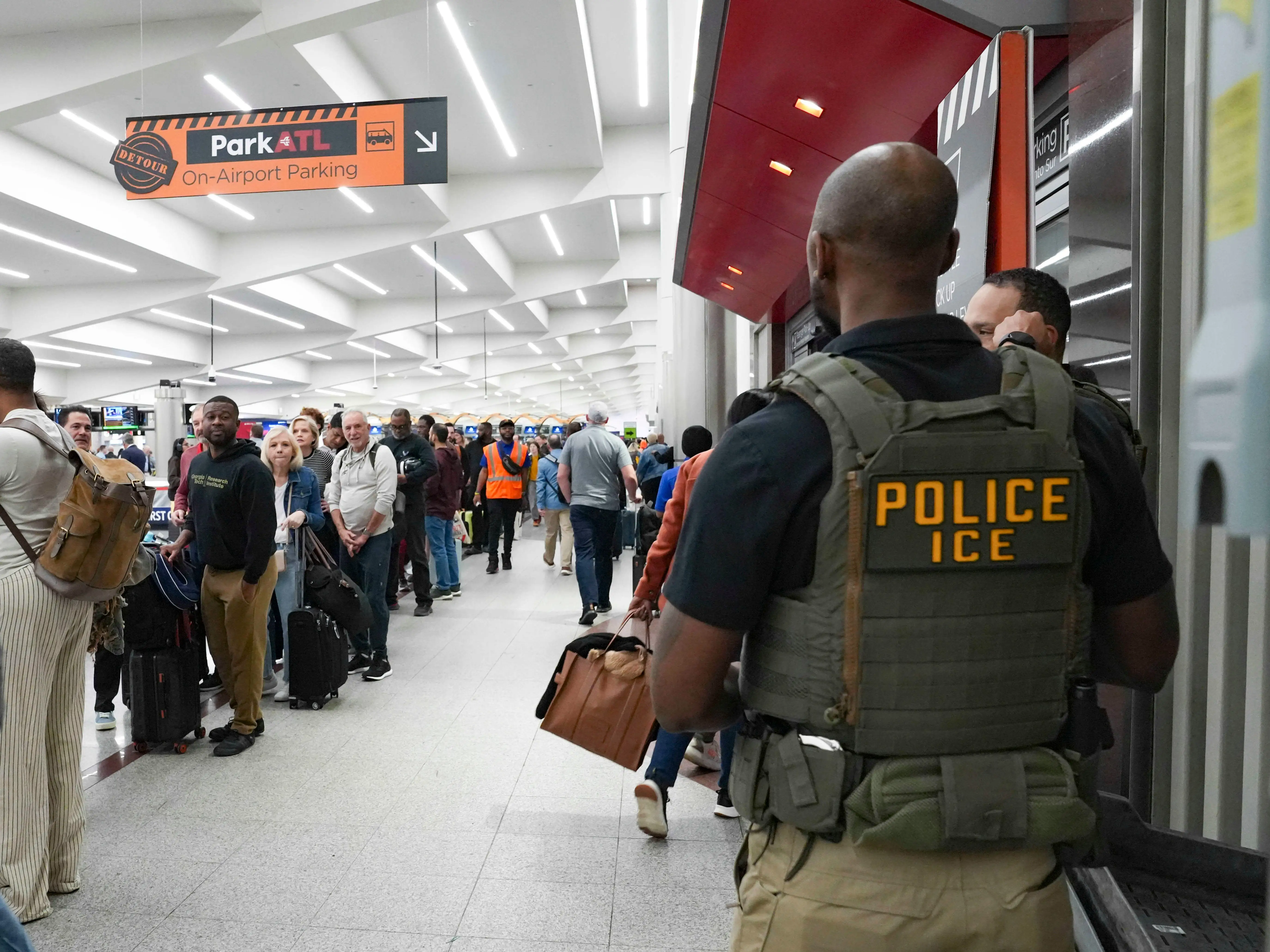 Ice agents look on as travelers stand in long lines at Atlanta Hartsfield-Jackson International Airport on March 23, 2026 in Atlanta, Georgia.